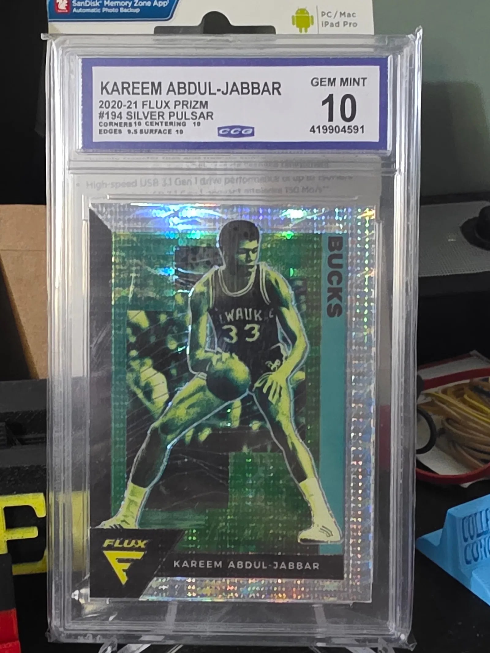 2020-21 Panini Flux Silver Pulsar Prizm #194 Kareem Abdul-Jabbar CCG Gem Mint 10: The product is a 2020-21 Panini Flux Silver Pulsar Prizm trading card featuring Kareem Abdul-Jabbar from the Milwaukee Bucks. This card is part of the National Basketball Association (NBA) set and is 