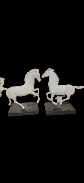 Pair of White Matte Porcelain Horses: This pair of white matte porcelain horse sculptures features dynamic, rearing poses mounted on dark wooden rectangular bases. Each figure is elevated by a clear acrylic support, giving the horses a fl
