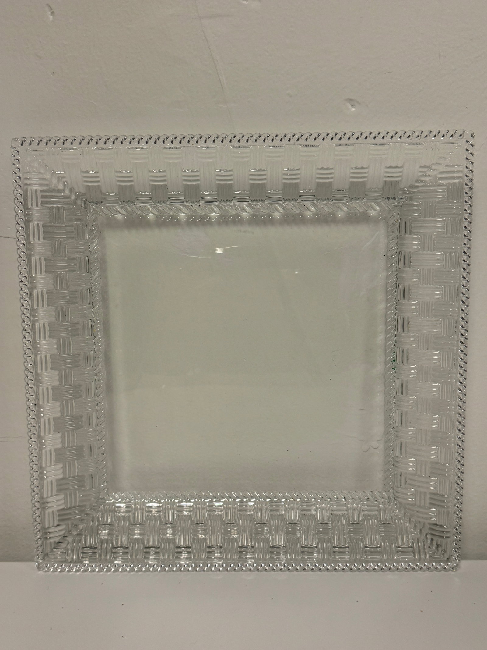 Tiffany & Co Basketweave Glass Tray: This elegant clear glass tray features a wide basketweave textured border and a smooth flat center. A rope-twist detail outlines the rim, adding a classic touch to the square silhouette. The piece is 