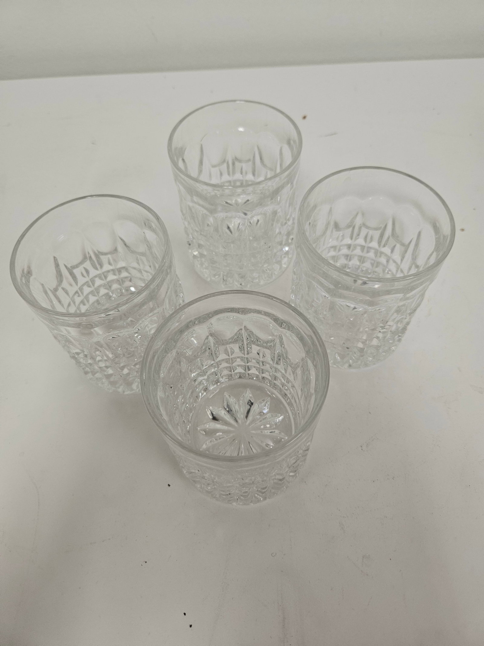 Set of 4 Pressed Glass Waffle Tumblers: This set of four tumblers features a pressed glass design with a classic waffle and starburst pattern. Each glass is crafted with a heavy base and an intricate textured exterior for a secure grip. The