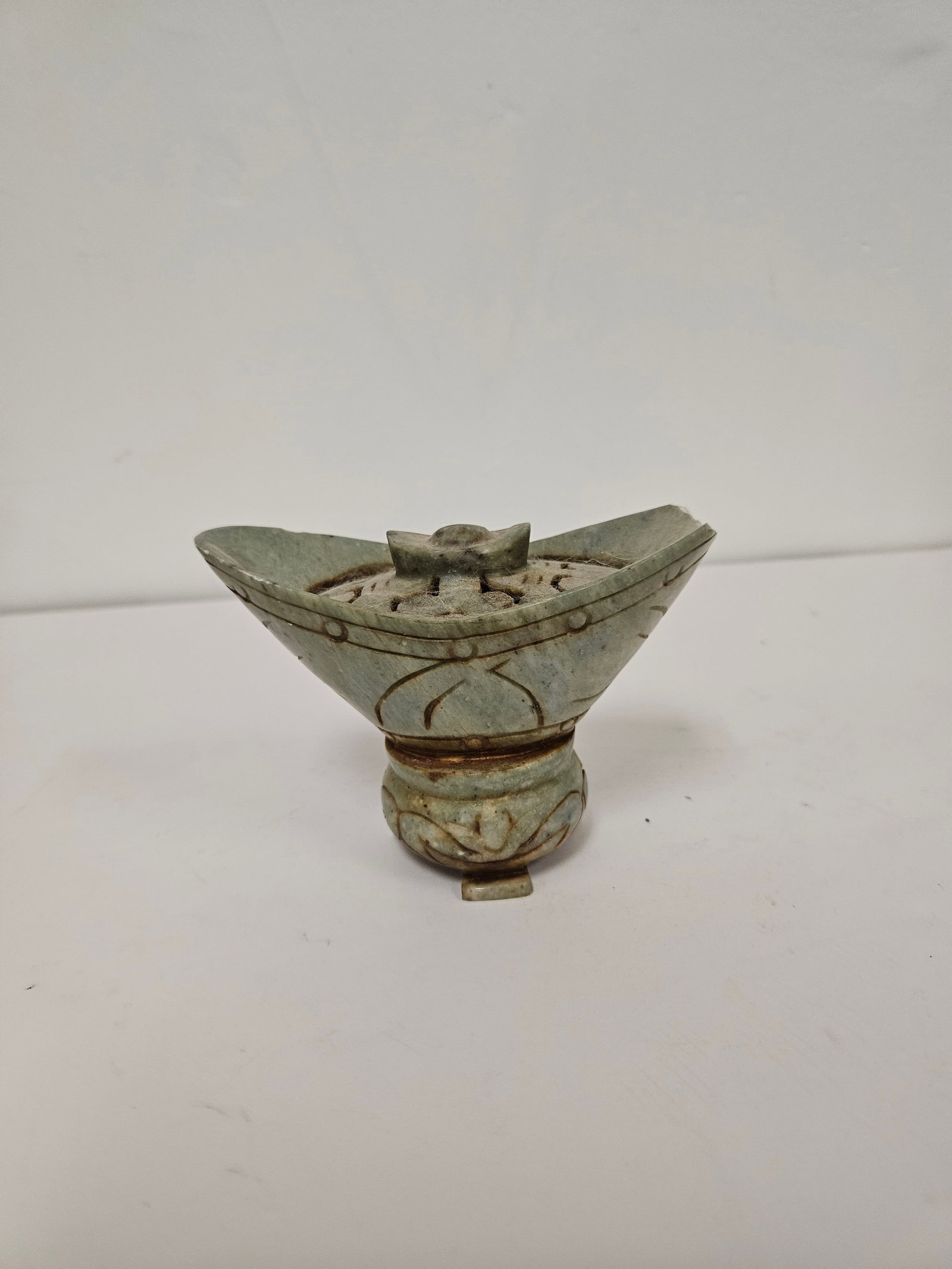 Damaged Archaic Style Carved Stone Vesse: This carved hardstone decorative piece features a tapered form with a pierced lid and incised geometric patterns. The vessel appears to be carved from a mottled green stone in an archaic style with a