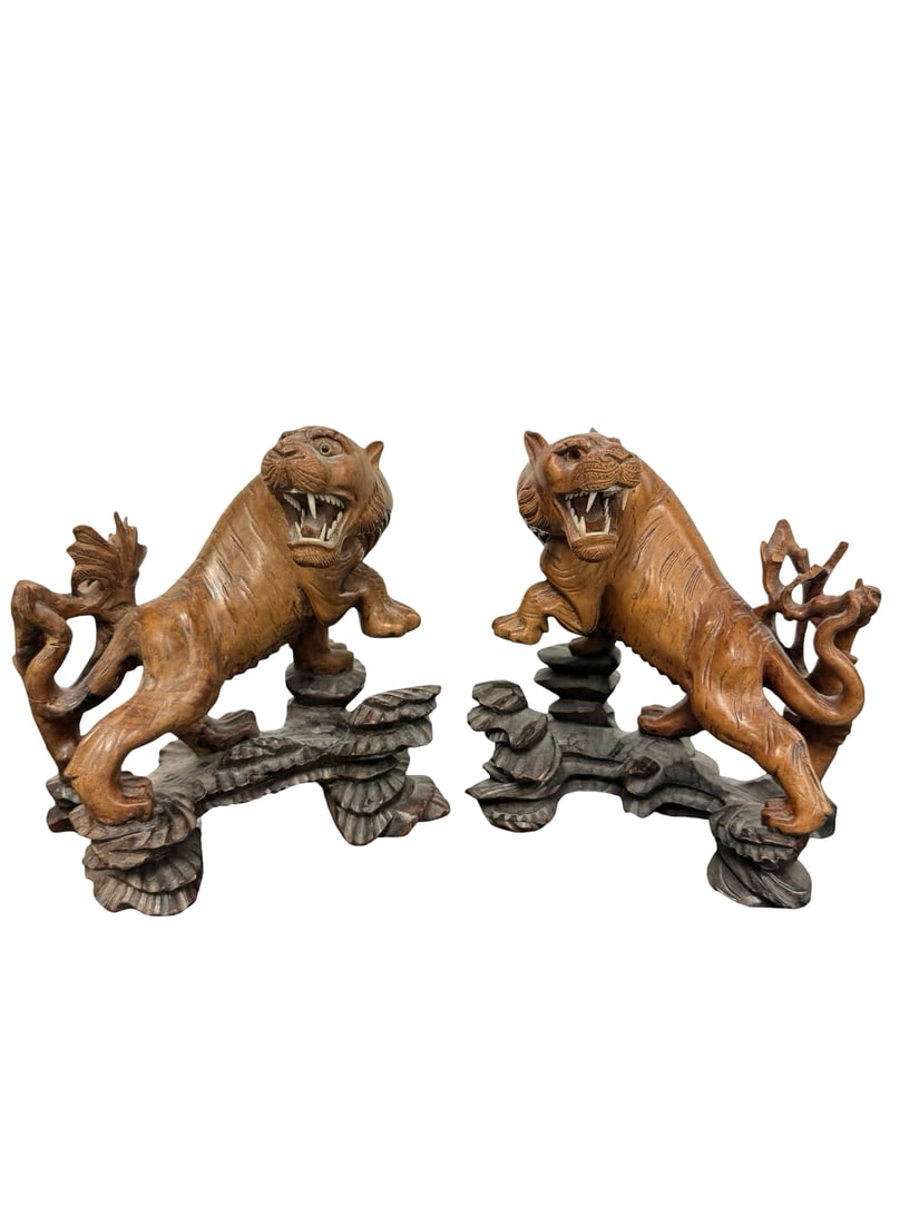 Pair of Large Hand-Carved Wooden Tigers: A pair of detailed hand-carved wooden tiger sculptures depicted in dynamic, prowling poses upon rocky cliff bases. Each tiger features an aggressive facial expression with visible teeth and inset