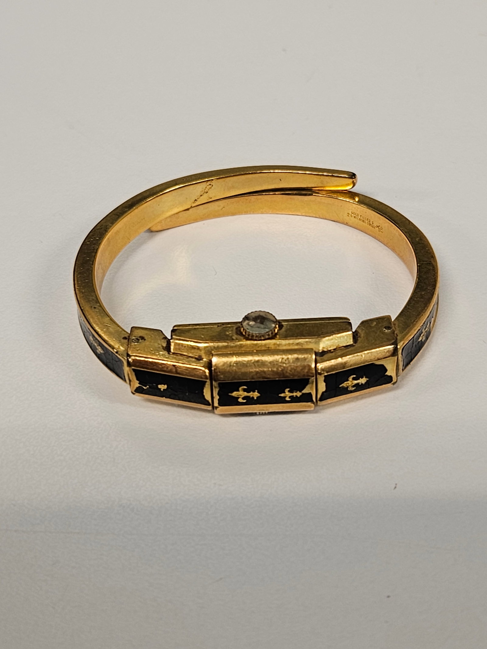 Vintage Kent Enamel Bangle Hidden Watch: This vintage Kent brand watch features a concealed flip-top dial integrated into a gold-filled bypass style bangle bracelet. The exterior is decorated with black enamel and gold-tone fleur-de-lis