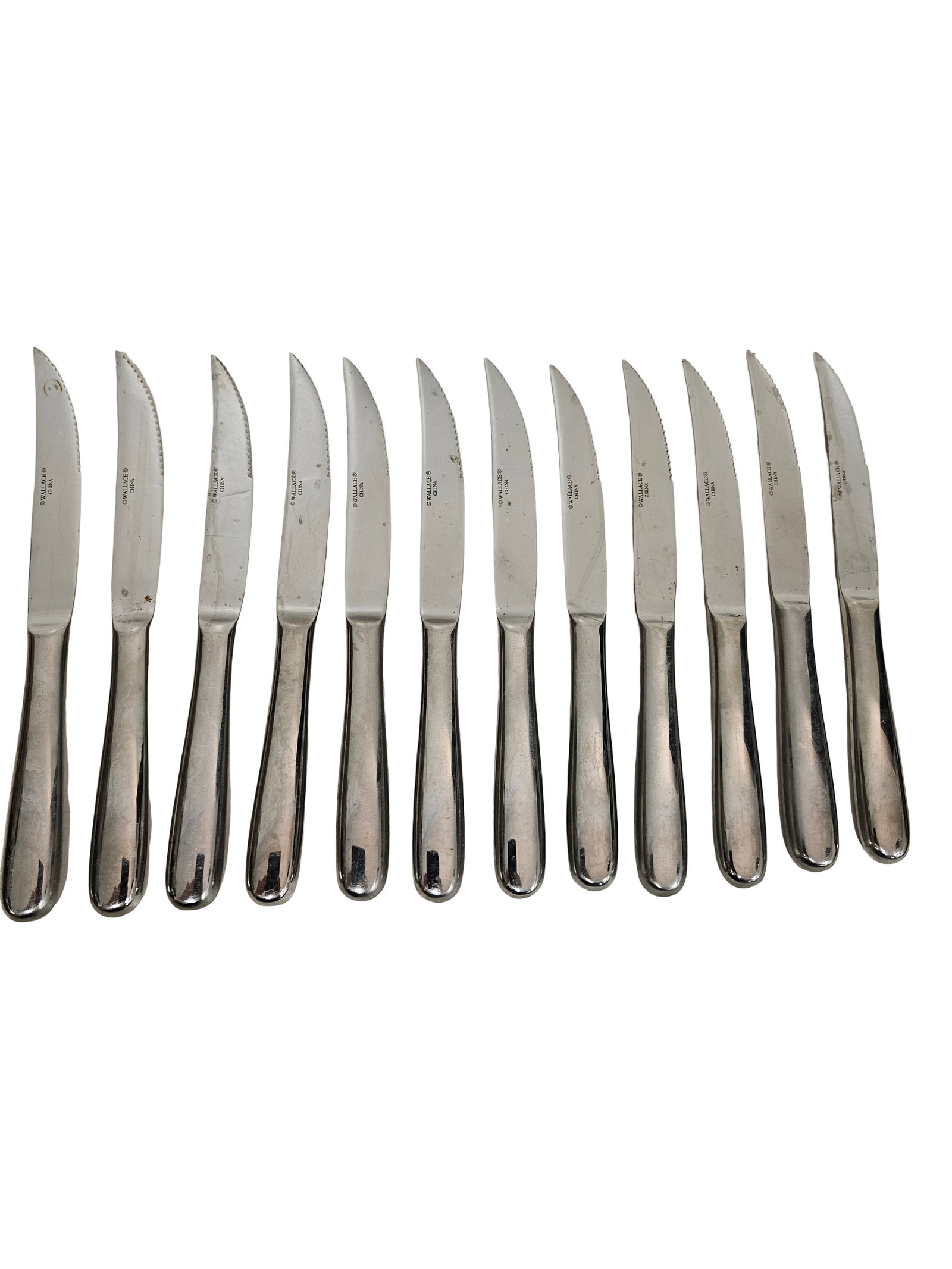 Set of 12 Wallace Stainless Steak Knives: This lot includes twelve stainless steel steak knives marked by Wallace China. Each knife features a serrated blade and a weighted, hollow-handle design with a polished finish. The set presents a