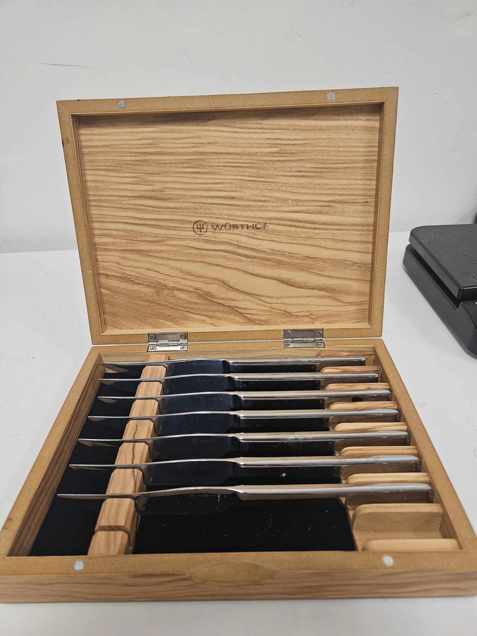 Set of 8 Wüsthof Style Steak Knives: This set includes eight stainless steel steak knives featuring a sleek, contemporary design with integrated handles. Each blade bears the Wüsthof hallmark, and they are housed in a fitted light-c