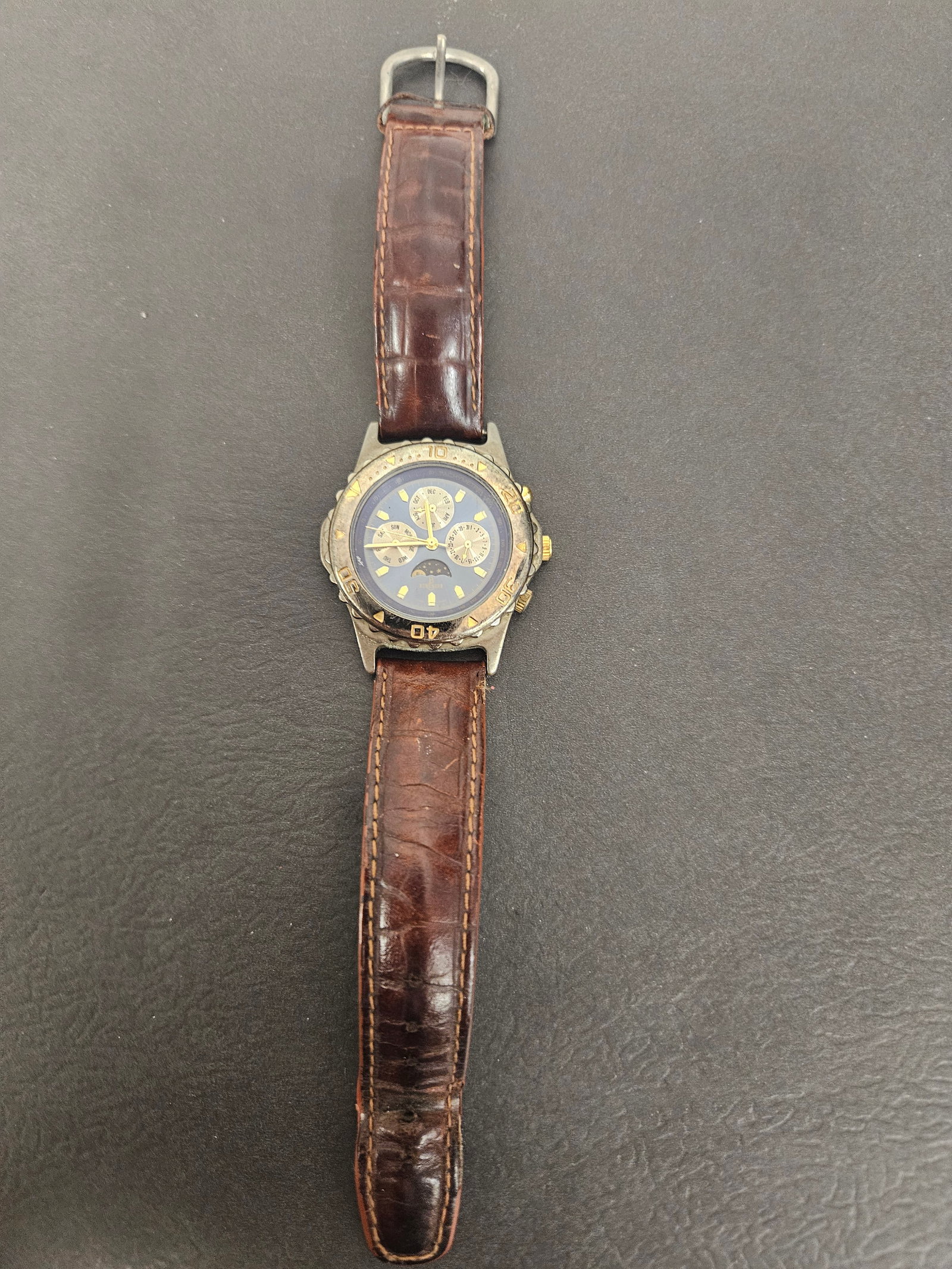 Berenger Moon Phase Calendar Wristwatch: This Berenger quartz wristwatch features a complex blue dial with moon phase and calendar subdials for day, date, and month. The case is a two-tone base metal with a rotating-style bezel and gold-tone