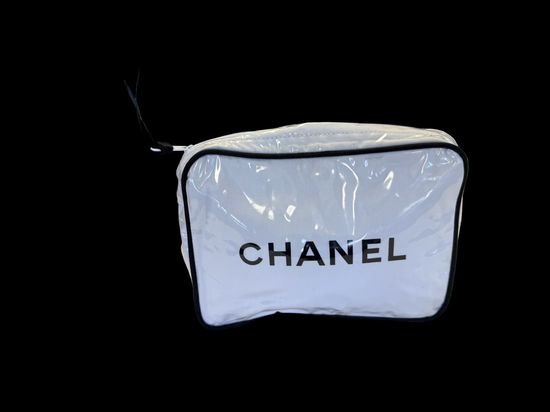 Chanel-Style Vinyl Cosmetic Pouch: This white vinyl cosmetic pouch features a prominent black printed logo on the front panel and a top zipper closure with a ribbon pull. The design includes black piping and a clear vinyl overlay for w