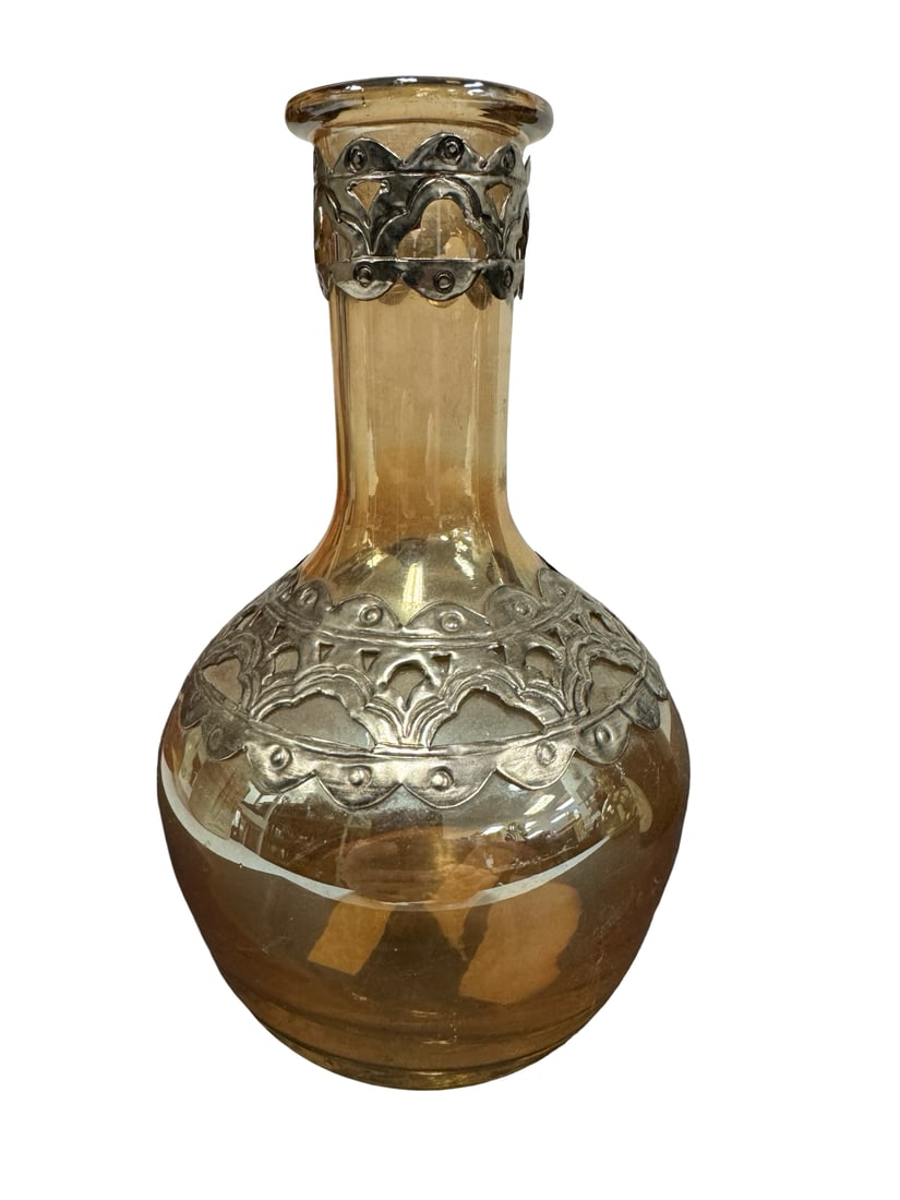 Bella Lux Amber Mercury Glass Metal Over: This decorative mercury glass vase features a warm amber hue and is accented with intricate silver-tone metal overlays at the neck and shoulder. The bulbous body tapers into a slender neck, creating