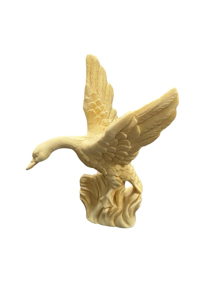Vintage Style Carved Faux Bone Goose Fig: This molded resin figurine depicts a goose or swan in flight, rising from turbulent water. The piece features detailed feathering and a creamy, off-white finish designed to mimic the appearance of car