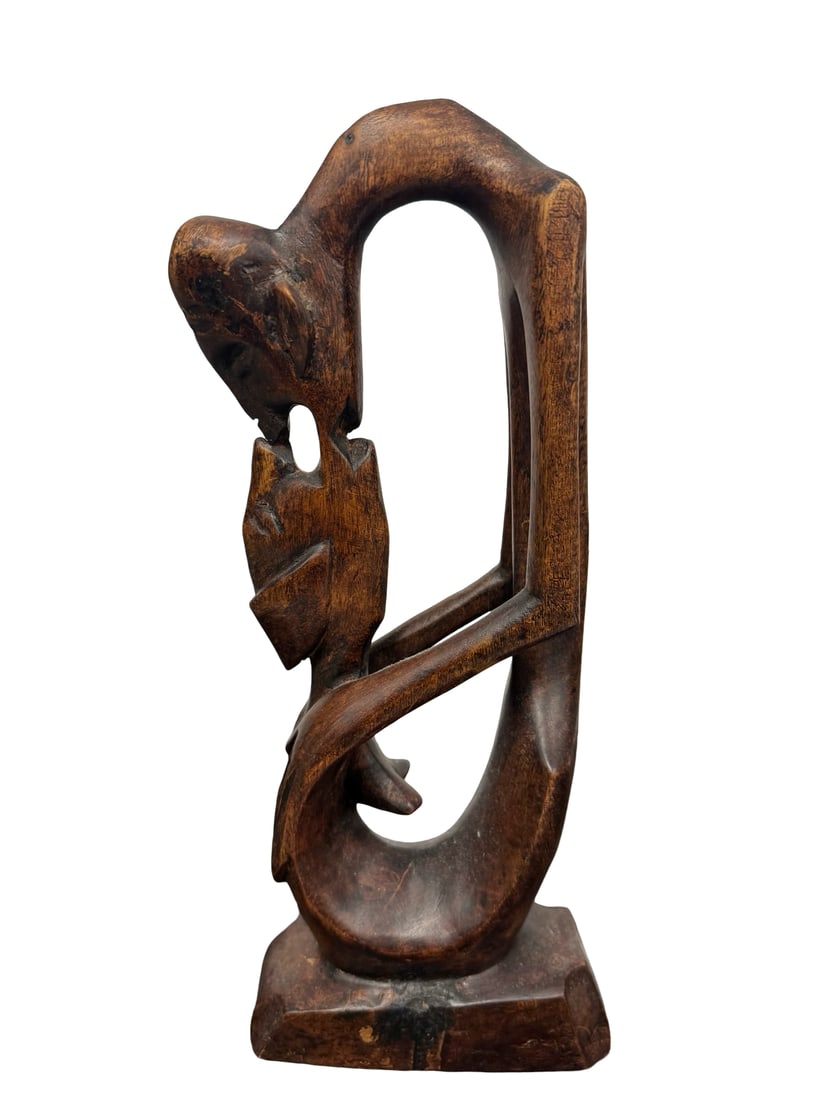 Abstract Hand-Carved Wooden Sculpture: This hand-carved wooden sculpture features an abstract representation of two figures in an intimate embrace. The piece is rendered in a stylized, elongated form with a rich, dark brown finish. It stan