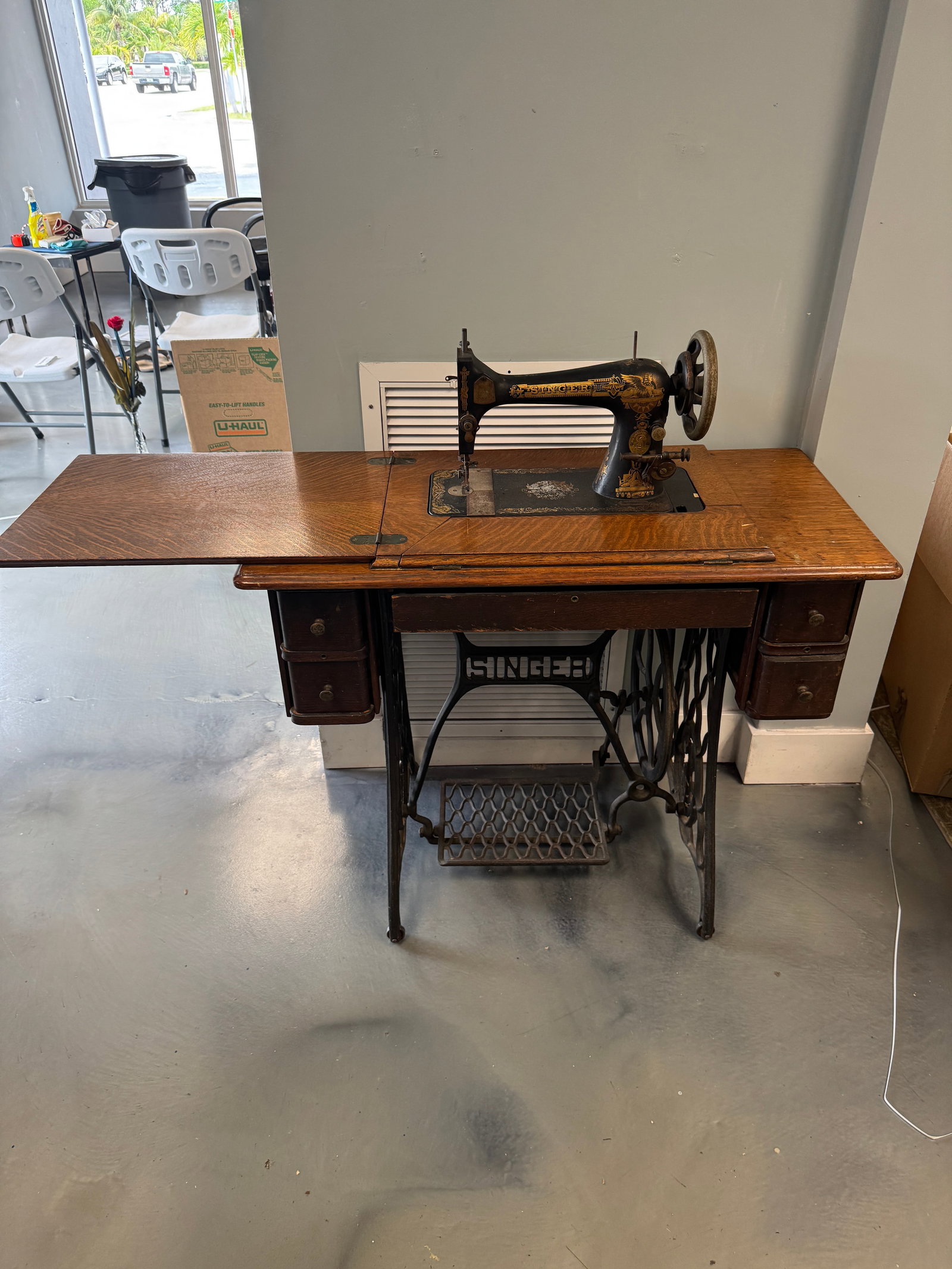Singer Treadle Sewing Machine in Oak Cab: Antique Singer treadle sewing machine housed in a quarter-sawn oak cabinet with five drawers. The sewing head features ornate gold-tone Victorian-style decals and a cast iron body with original Singer