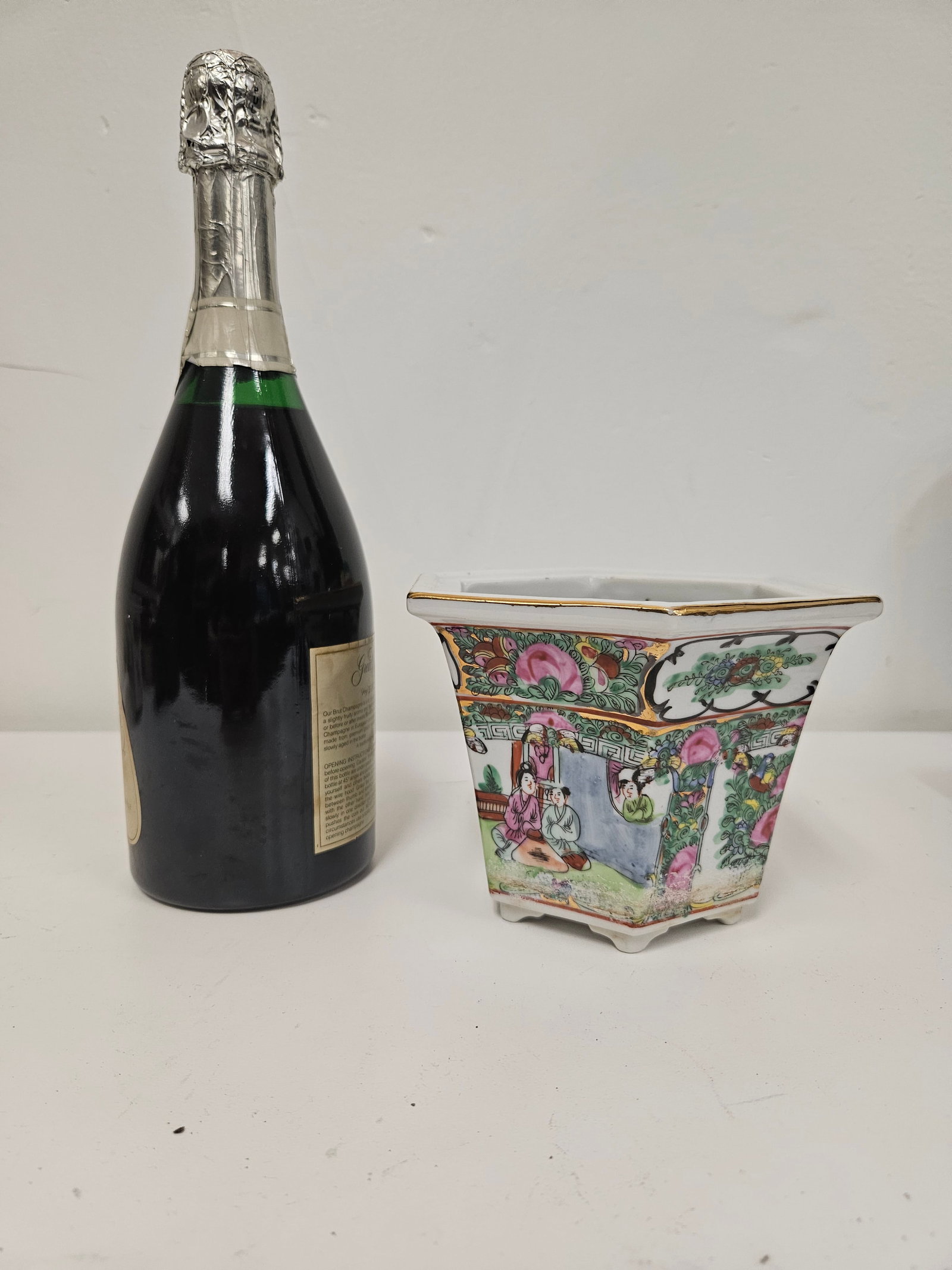 Rose Medallion Style Hexagonal Planter: This hexagonal porcelain planter features vibrant Rose Medallion style panels depicting floral motifs and interior court scenes. The tapered form is accented with a gilt rim and sits on six small