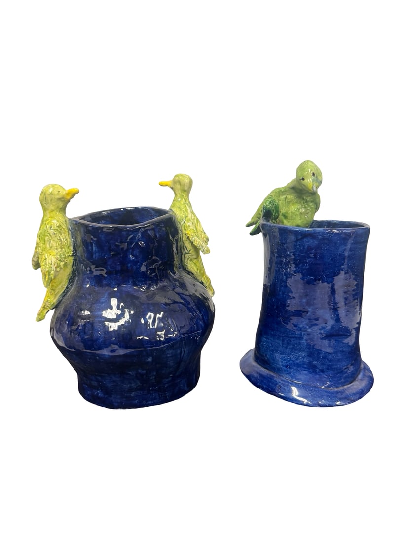 Pair of Artisan Cobalt Blue Bird Pottery: This pair of handmade studio pottery vessels features a vibrant cobalt blue glaze with stylized green bird figures perched on the rims. The set includes one bulbous vase with two birds and one cylindr