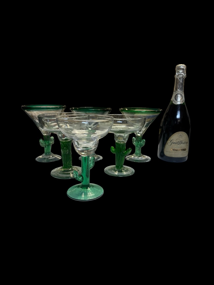 Set of 7 Hand-Blown Cactus Stem Glasses: This set includes 7 hand-blown glasses featuring vibrant green saguaro cactus stems and clear bowls. Three of the glasses are designed in a classic martini shape with green rims, while the other