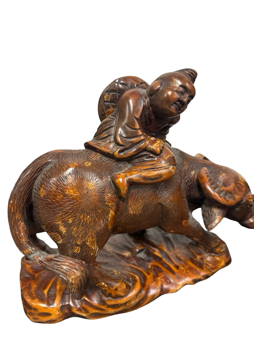 Chinese Style Carved Wood Boy on Buffalo: A hand-carved wooden figure depicting a smiling young boy or immortal riding on the back of a water buffalo. The sculpture features textured carving to simulate animal fur and a woven hat detail on th