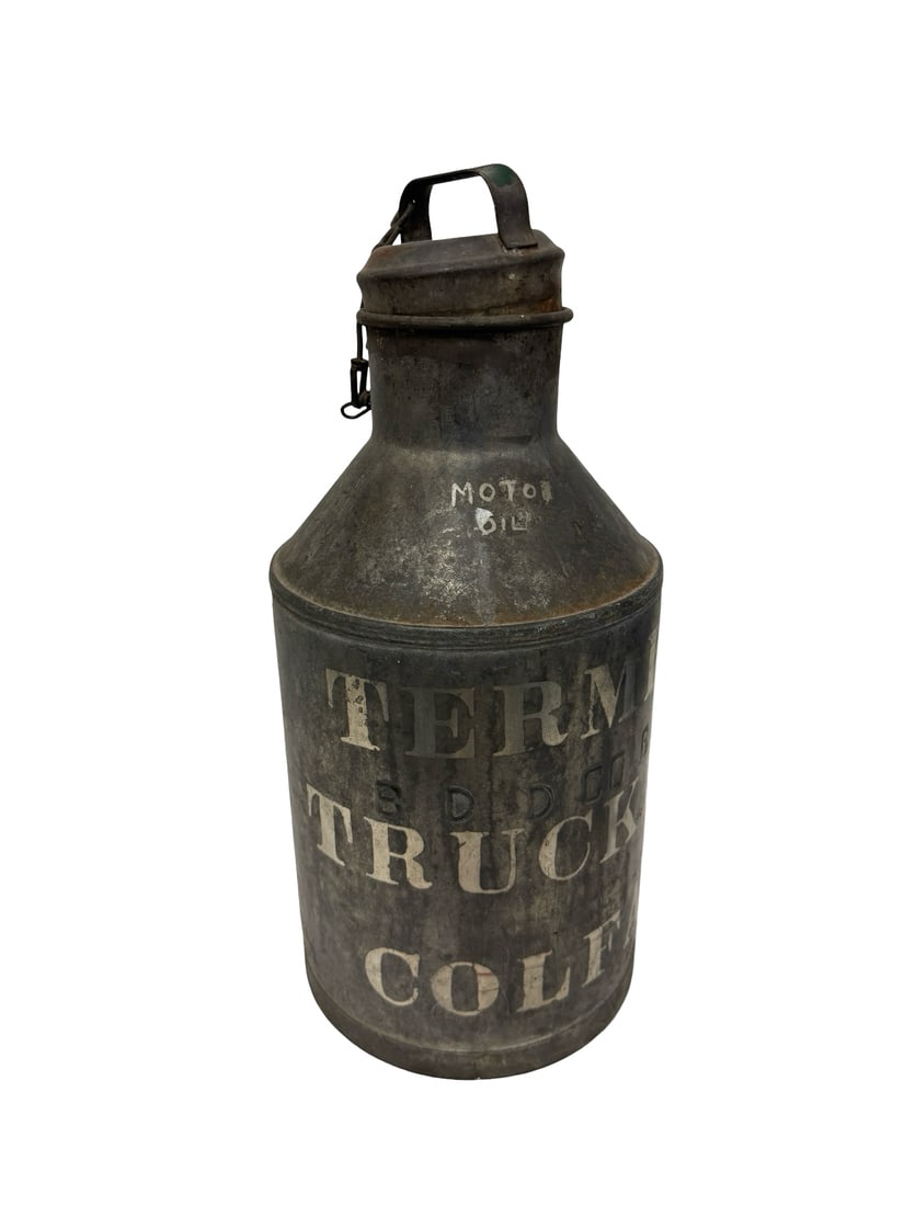 Vintage Stenciled Motor Oil Canister: This vintage industrial motor oil canister features a weathered galvanized metal body with a chained cap and side handle. The front is adorned with original white stenciled lettering advertising 'MOTO