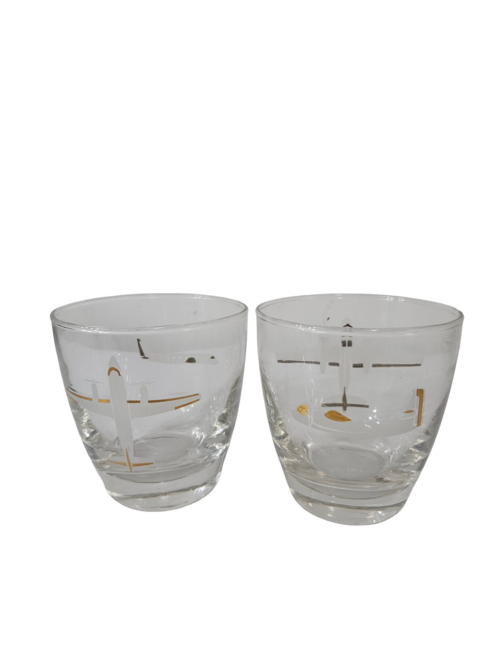 Vintage Mid-Century Aviation Glasses-2pc: This pair of vintage rocks glasses features a mid-century modern aesthetic with white and gold-tone airplane graphics. The tapered glassware includes a thick base, characteristic of 1950s or 60s