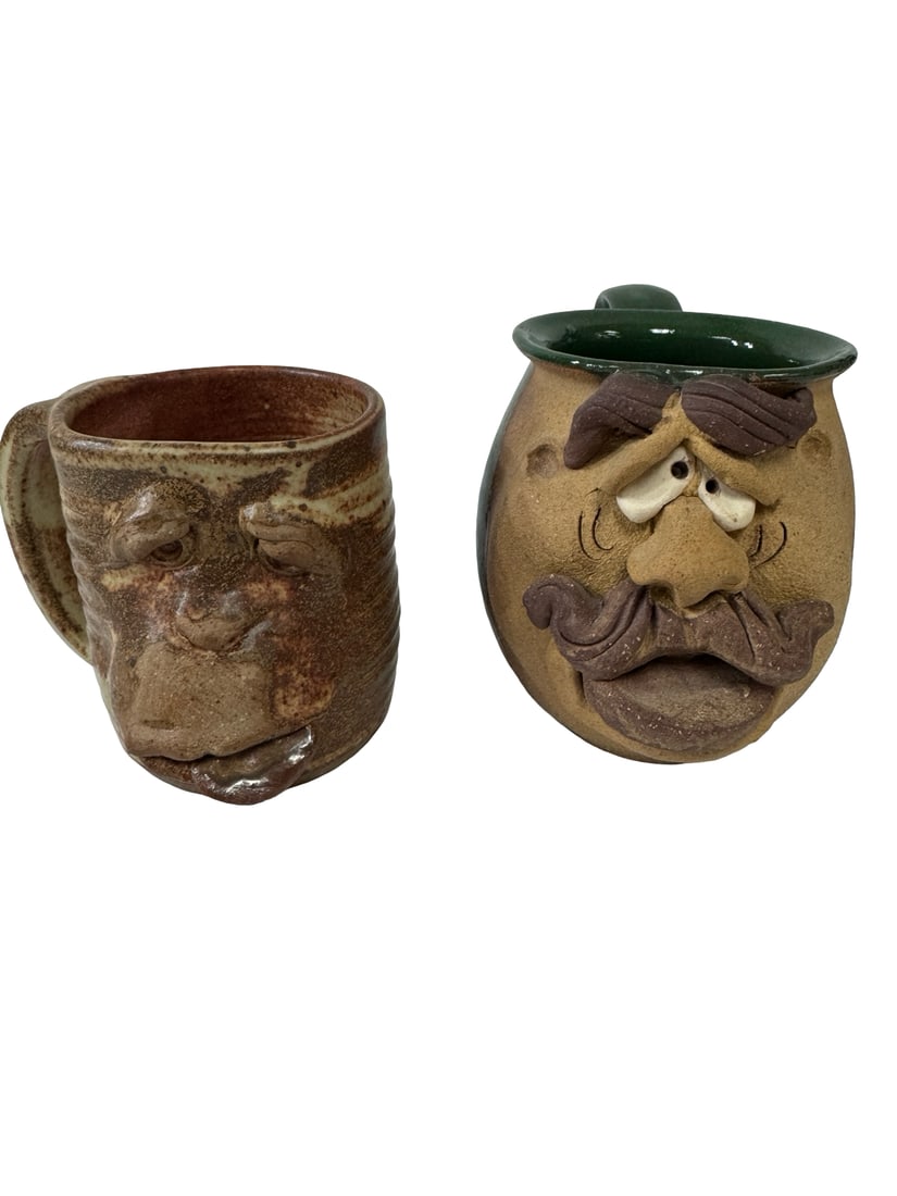 Two Studio Pottery Face Mugs, Hahn 93: This set includes two whimsical studio pottery face mugs featuring expressive, high-relief sculpted features. One mug is finished with a speckled earth-tone glaze and is signed 'Hahn 93' on the