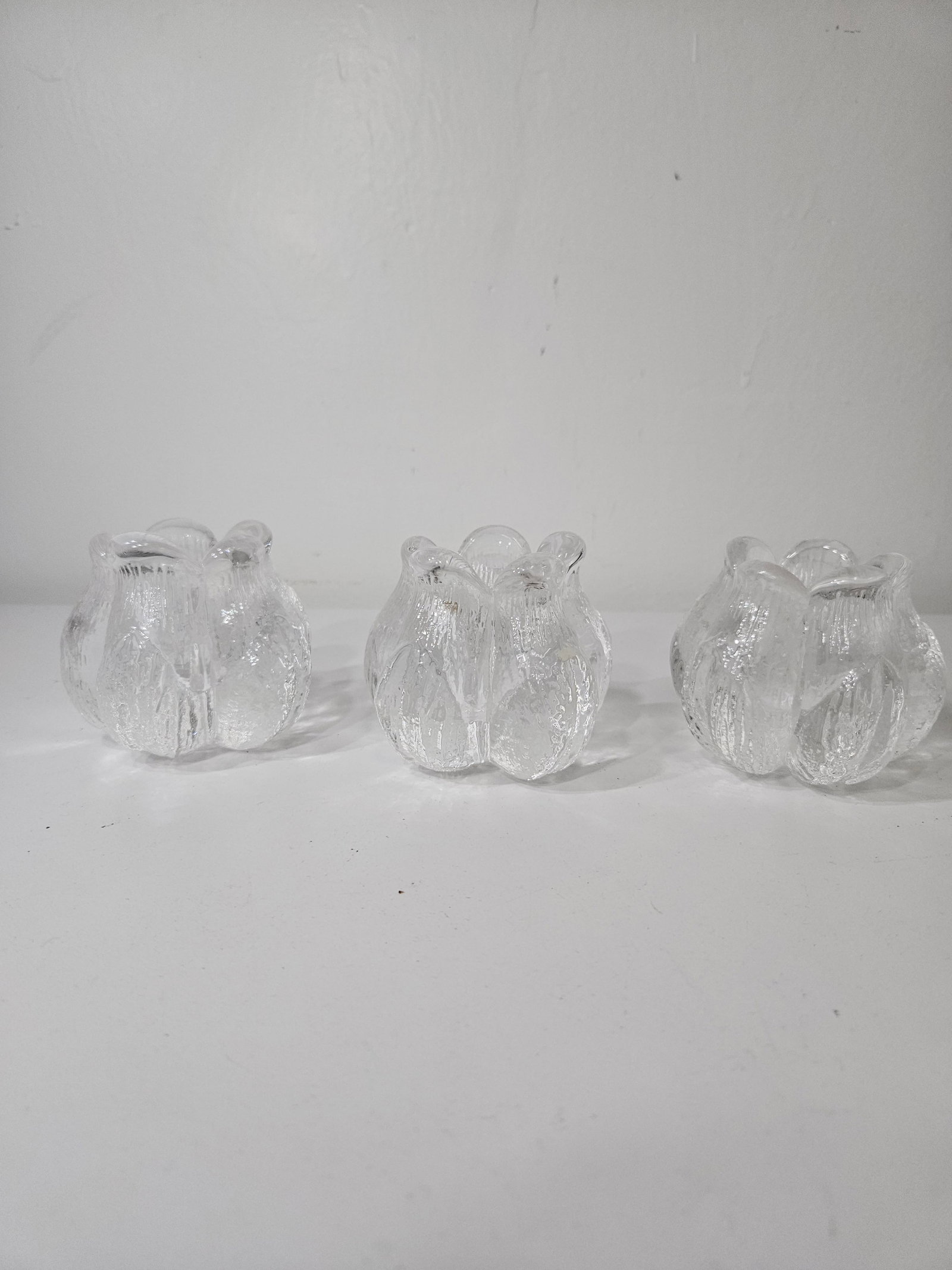 Set of 3 Textured Glass Tulip Votives: A set of three textured glass candle holders designed in a stylized tulip or floral bud shape. Each piece features a heavy molded glass construction with a frosted, bark-like exterior texture and smoo