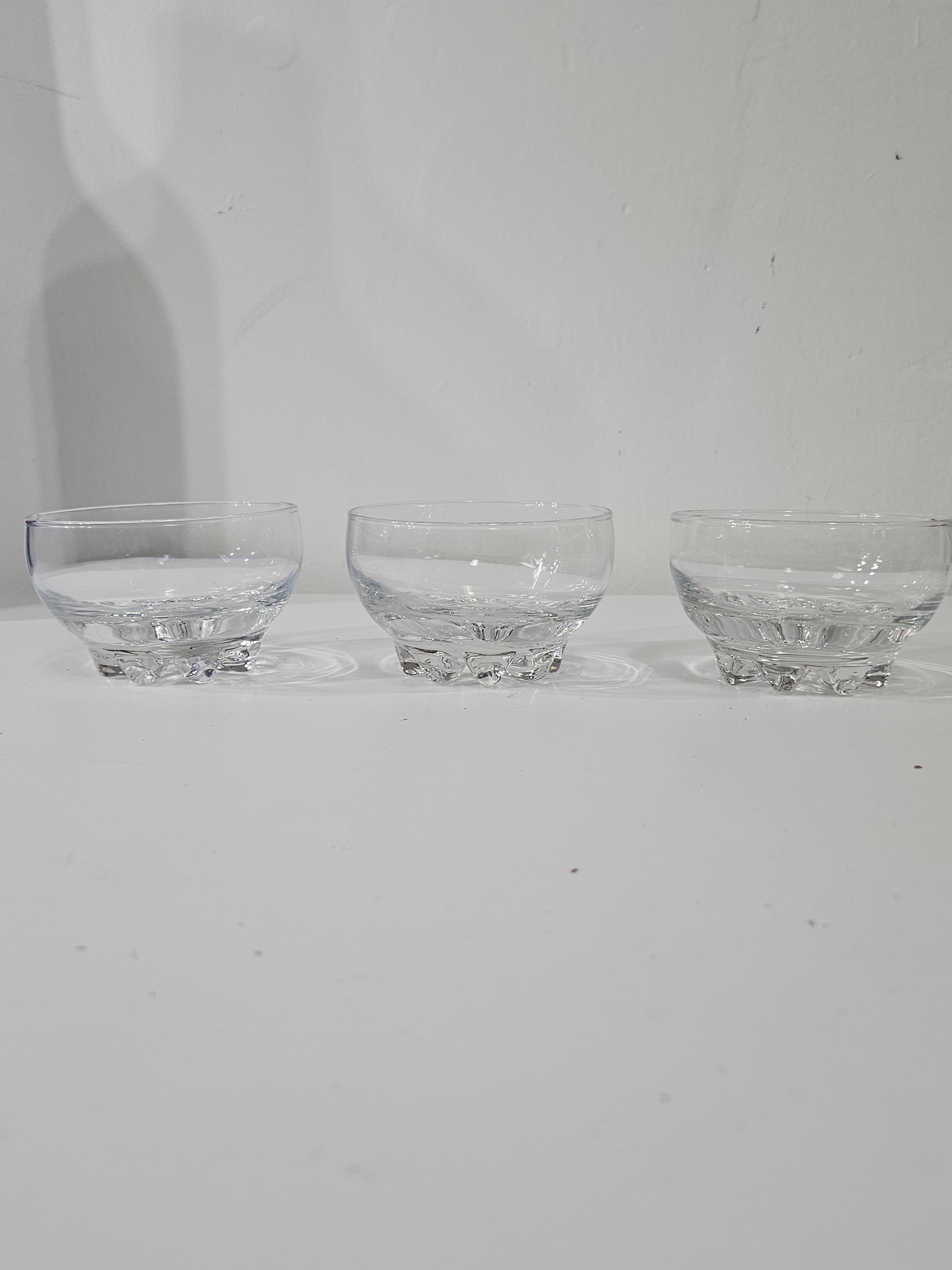 Set of 3 Glass Petal Base Dessert Bowls: A set of three clear pressed glass dessert or berry bowls featuring a distinctive textured petal base. Each bowl is designed with a simple rounded rim and a weighted bottom for stability. These versat