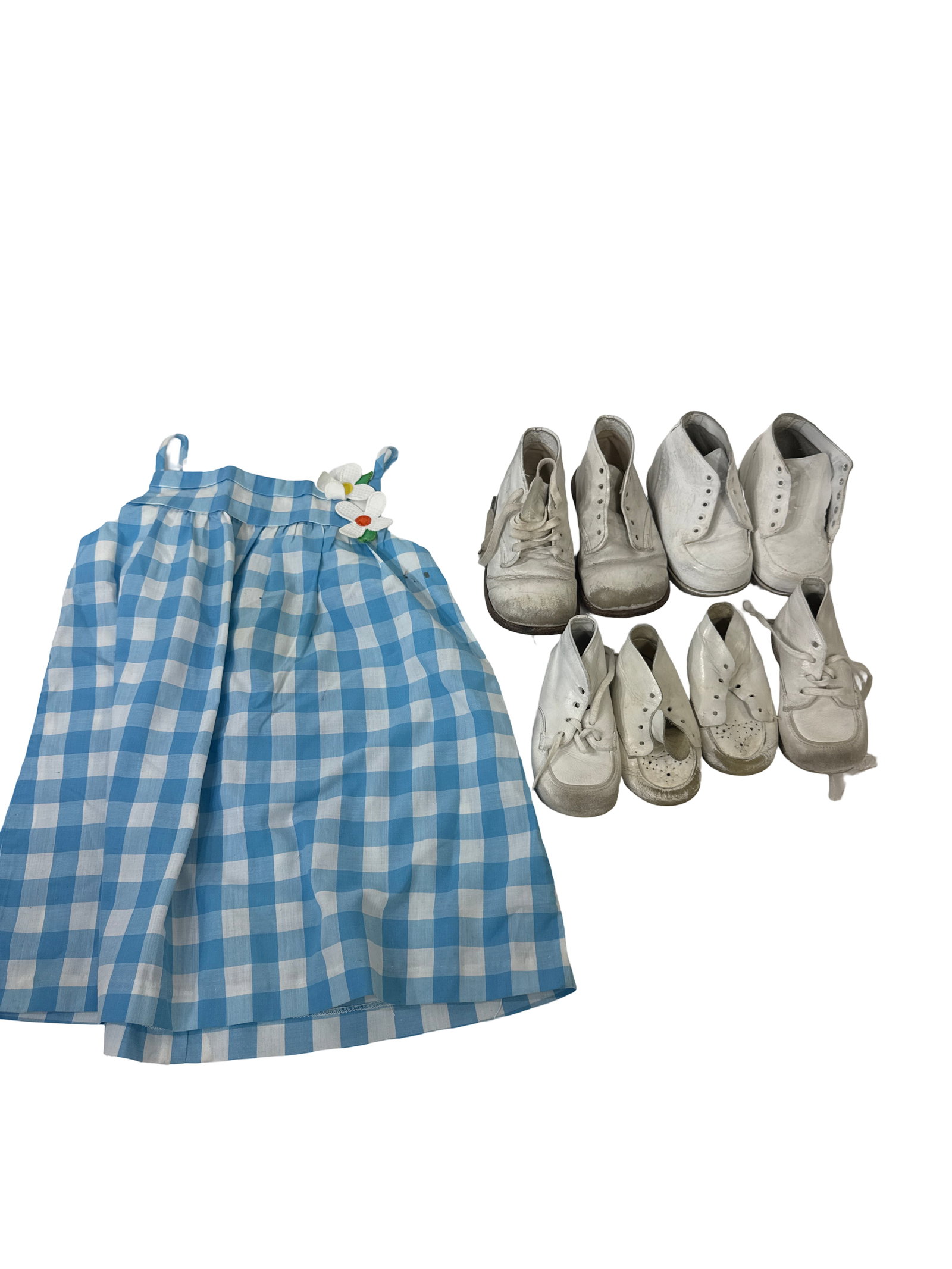 Vintage Gingham Dress & Baby Shoe Lot: This collection includes a vintage-style blue and white gingham toddler dress adorned with white floral accents. Accompanying the dress are four pairs of white leather infant walking shoes in various 