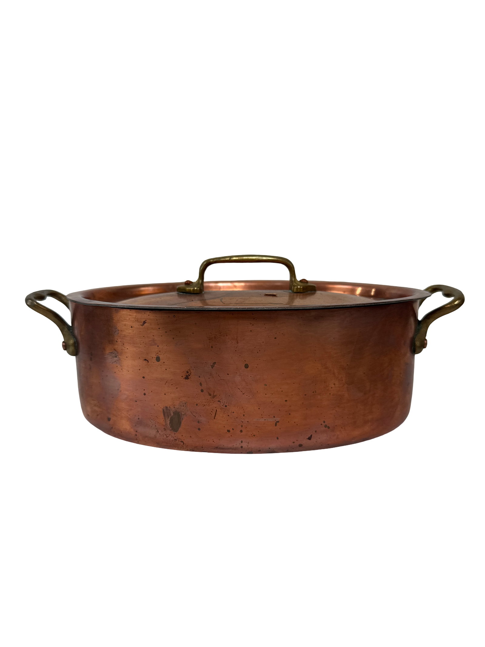 Oval Copper Cocotte with Brass Handles: This oval copper cocotte features a matching lid and brass hardware for a classic French country aesthetic. The piece exhibits a well-worn patina with a darkened interior tin lining consistent with ag