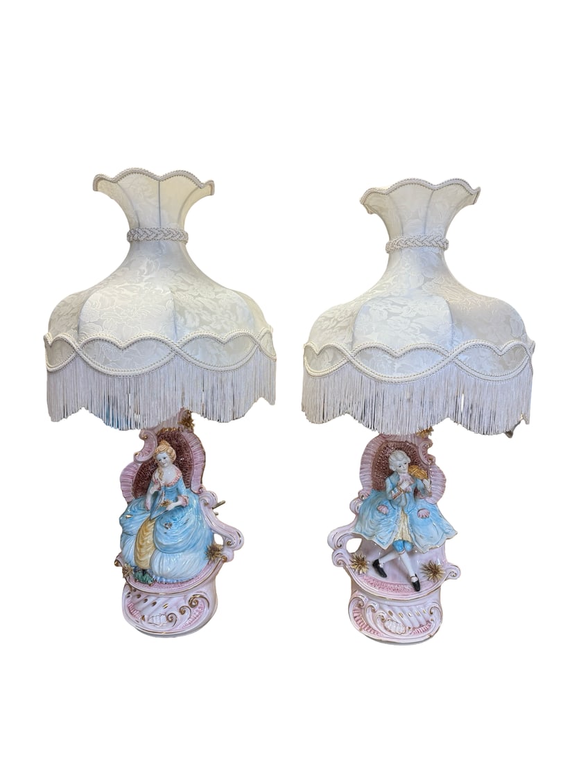 Pair of Rococo Style Porcelain Lamps: A pair of elaborate porcelain table lamps featuring Rococo-style figures of a courtly lady and a gentleman playing the violin. The bases are decorated with ornate pink and blue glazes, scrolling rocai