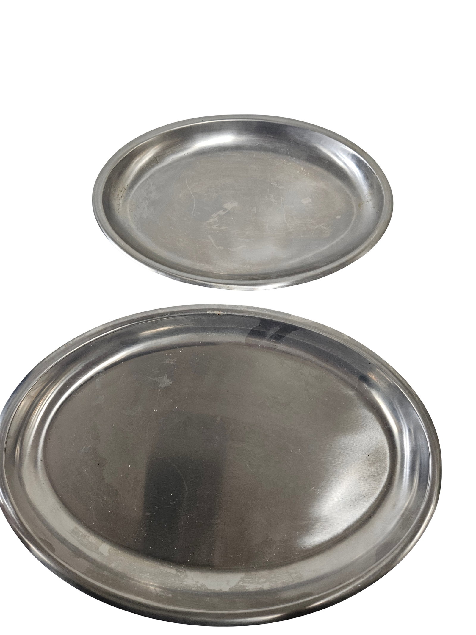 Pair of Oval Polished Metal Platters: This set includes two oval serving platters of differing sizes crafted from a polished silver-toned metal. The platters feature a simple, rolled rim design suitable for both formal and casual dining s