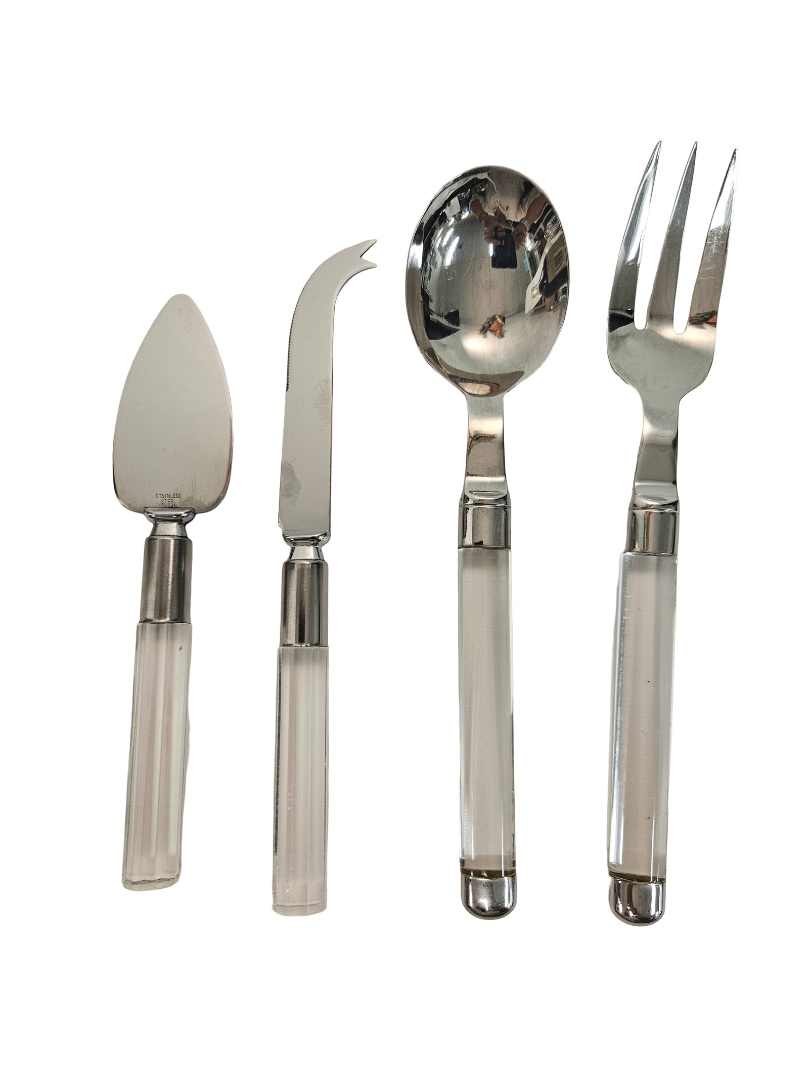 4pc Stainless Serving Set Lucite: This four-piece serving set features polished stainless steel heads and elegant clear Lucite faceted handles. The set includes a cheese spreader, a spade-shaped server, a serving spoon, and a three-ti
