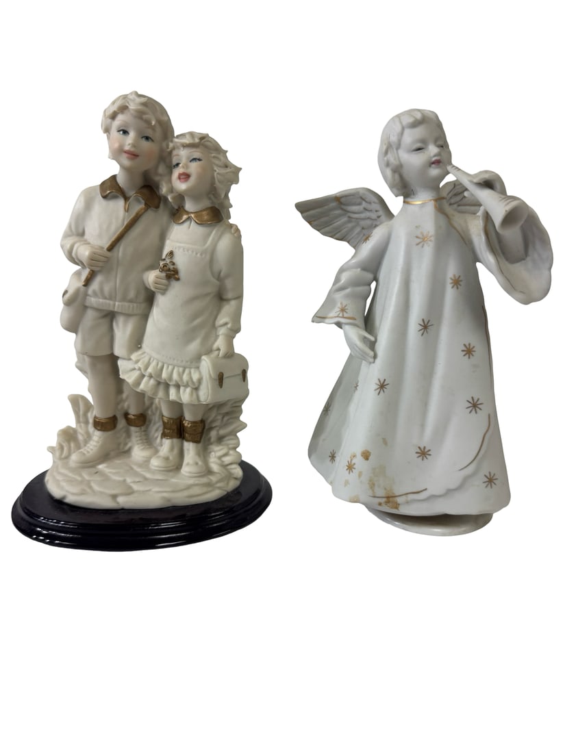 Two Vintage Porcelain Figurines Set: This lot features two vintage porcelain figurines, including a boy and girl pair and a winged angel. The double figurine depicts a school-aged couple in soft cream tones with gold-painted accents,