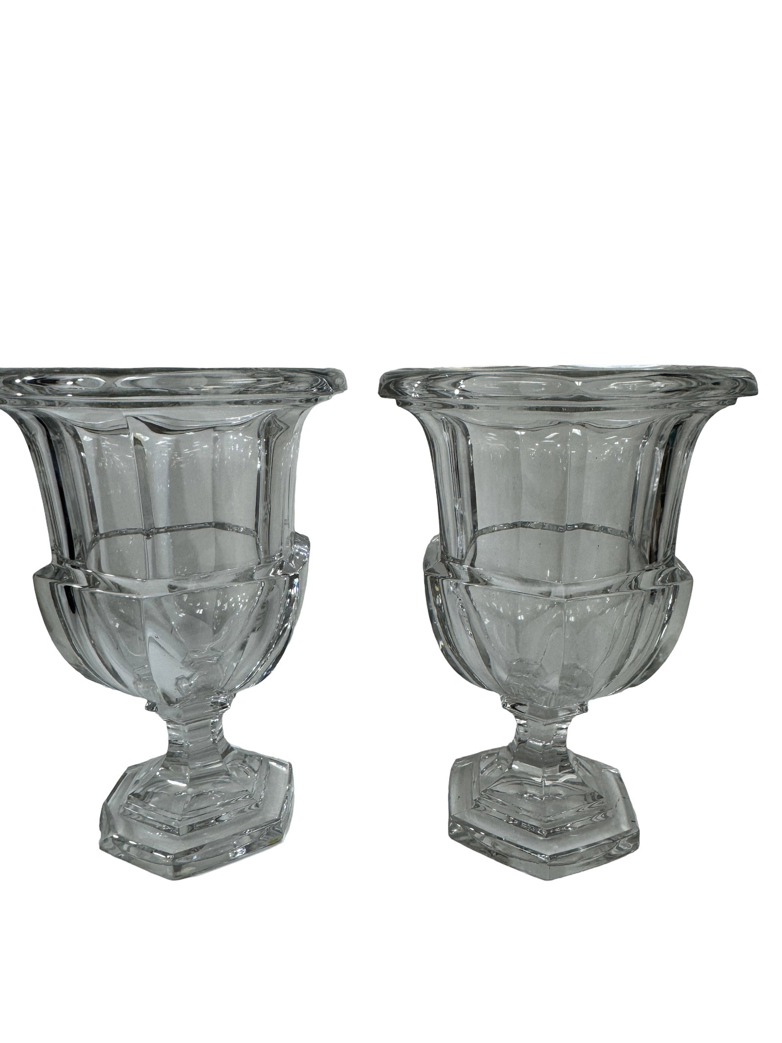 Pair of Large Clear Glass Urn Vases: This pair of heavy clear glass urn-style vases features a classical fluted design with flared rims. Each vessel is supported by a short faceted stem and a sturdy hexagonal footed base. The large scale