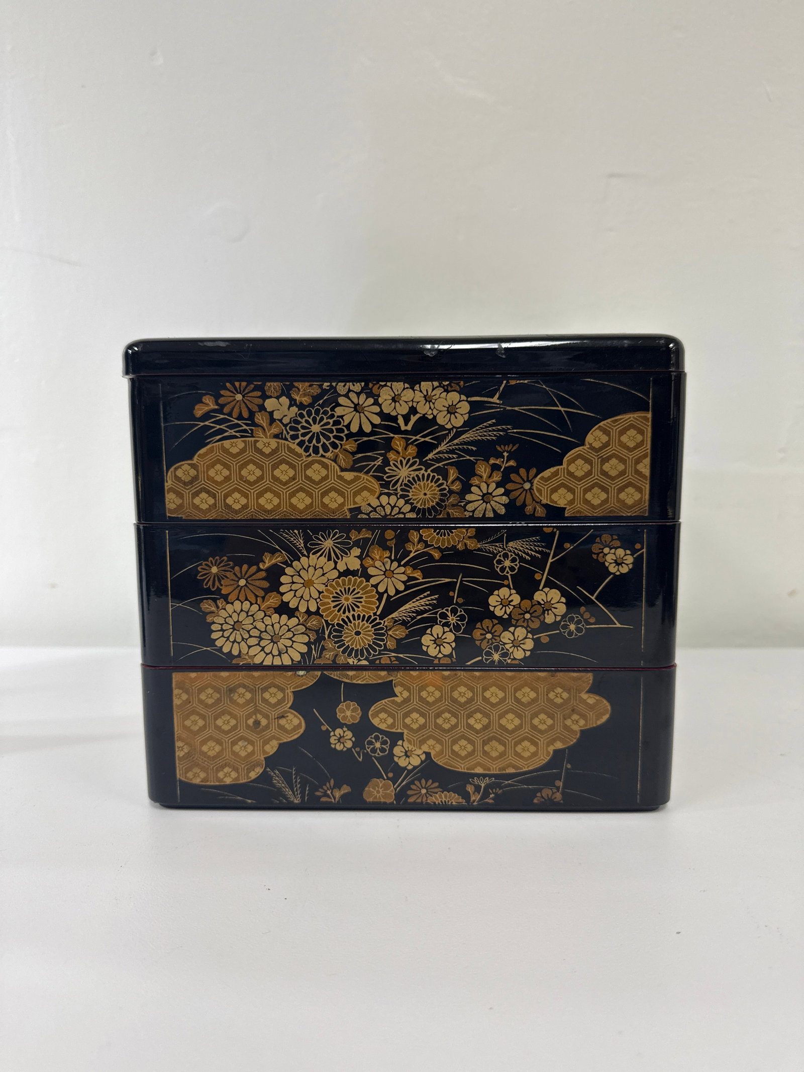 Japanese Style 3-Tier Lacquered Jubako: This Japanese-style three-tier jubako bento box features a black lacquer-inspired finish with vibrant red interiors. The exterior is decorated with traditional gold-tone floral and cloud motifs, inclu