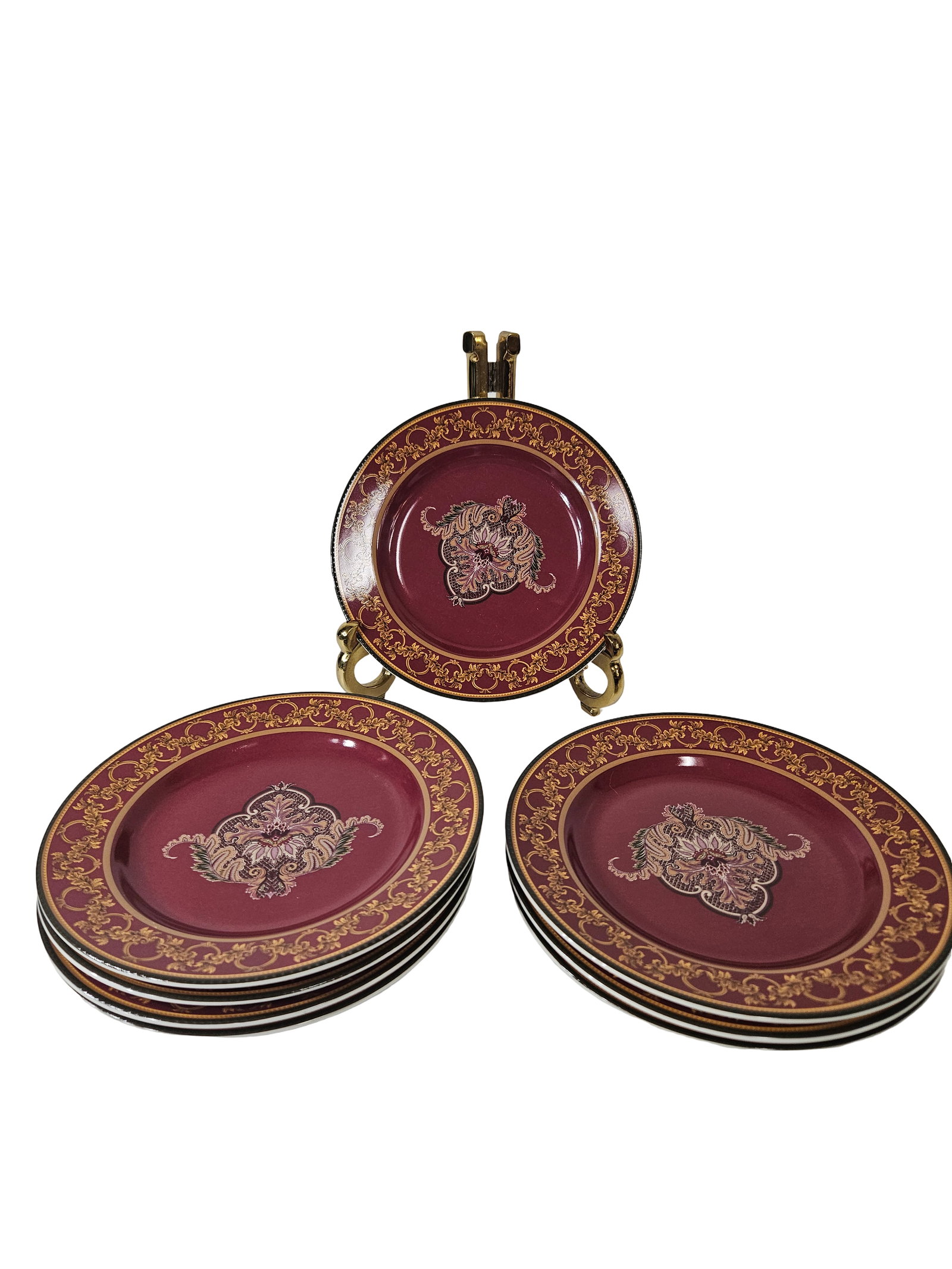 11 Raymond Waites Ancient Kingdom Plates: This collection includes eleven salad or dessert plates from the Ancient Kingdom pattern by Raymond Waites for Certified International. Each plate features a rich burgundy ground adorned with an