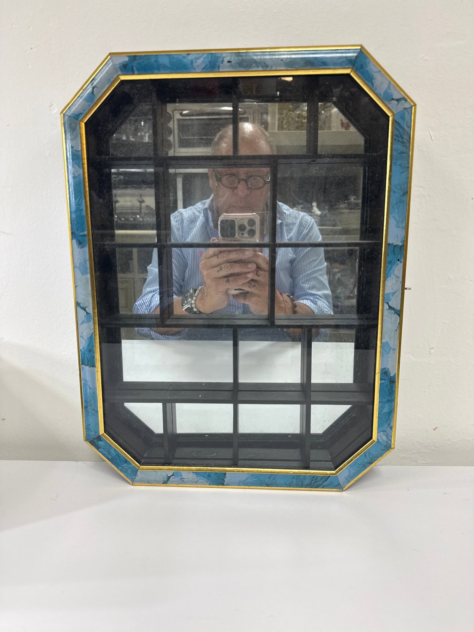 Octagonal Mirrored Wall Curio Cabinet: This octagonal wall-mounted curio cabinet features a mirrored back and a glass door with a gold-tone trim. The frame is finished in a decorative blue marbleized pattern with multiple interior cubbies