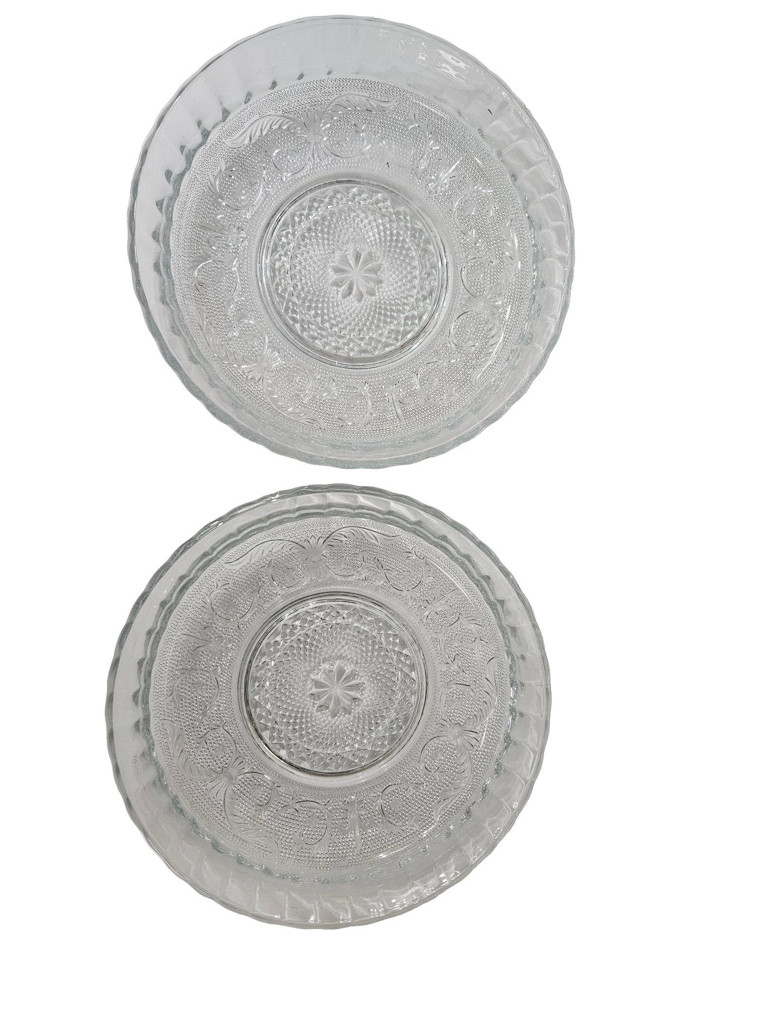 Two Large Pressed Glass Serving Bowls: This lot features two circular clear pressed glass serving bowls with an intricate starburst and floral motif. The bowls include a scalloped, ribbed rim and a textured stippled background within the