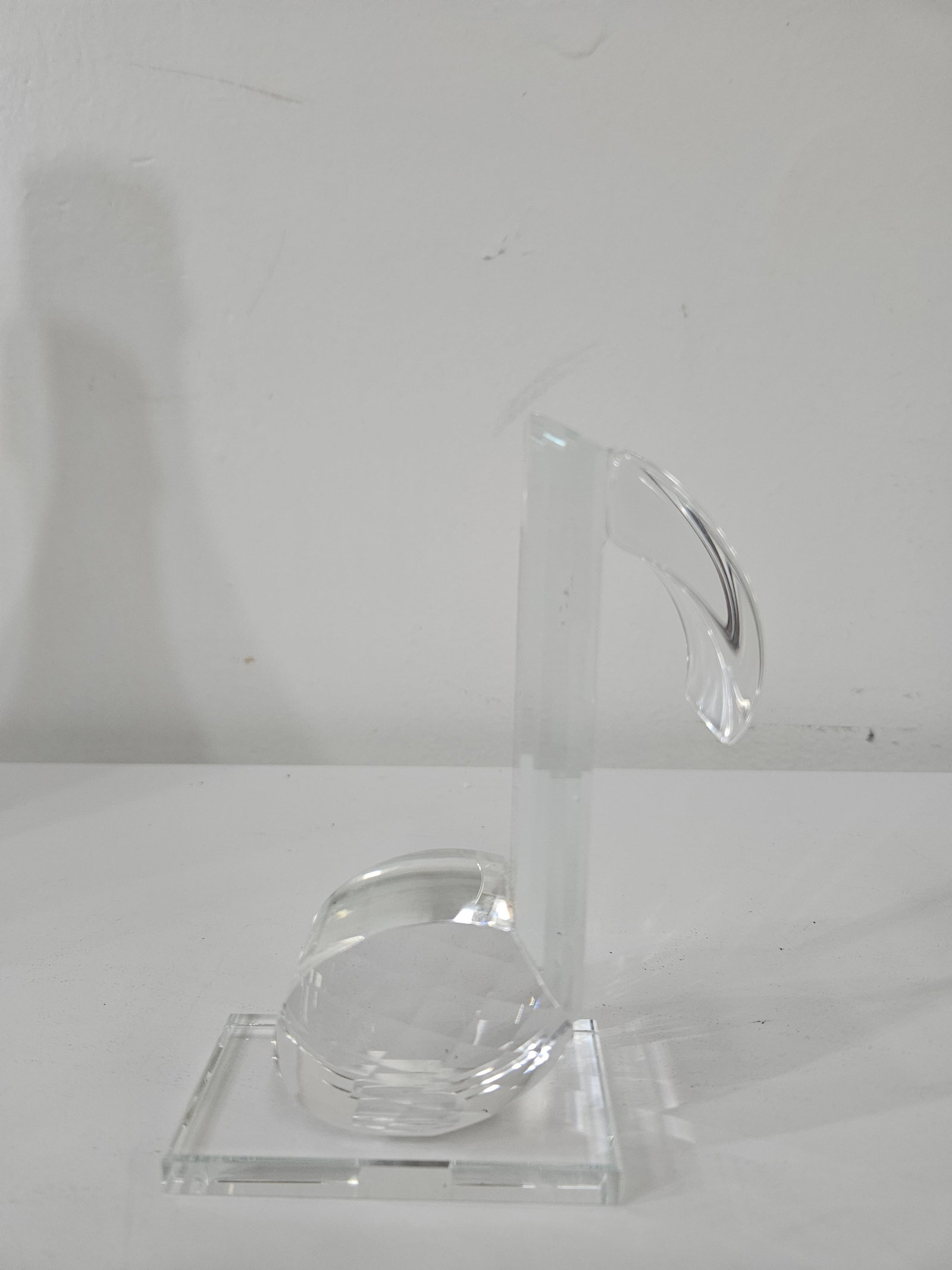 Modern Clear Glass Music Note Sculpture: This decorative glass paperweight is sculpted in the form of a musical eighth note with a faceted base portion. The piece features a clear, polished finish and sits atop an integrated rectangular glas