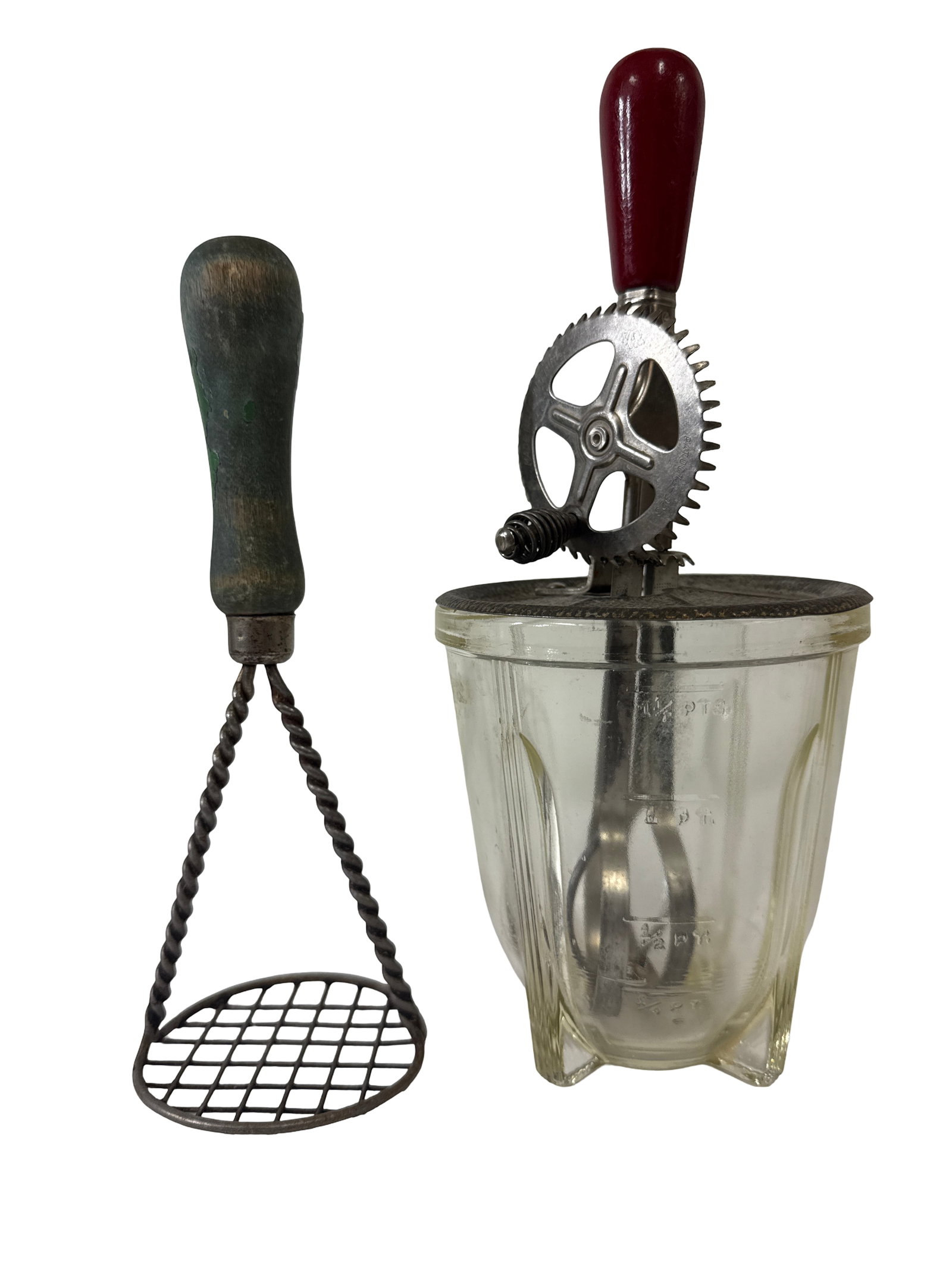 Vintage Egg Beater and Potato Masher: This lot features a vintage green-handled potato masher alongside a clear glass beaker with a red-handled hand-crank egg beater. The egg beater is marked with a 1923 patent date and includes its origi