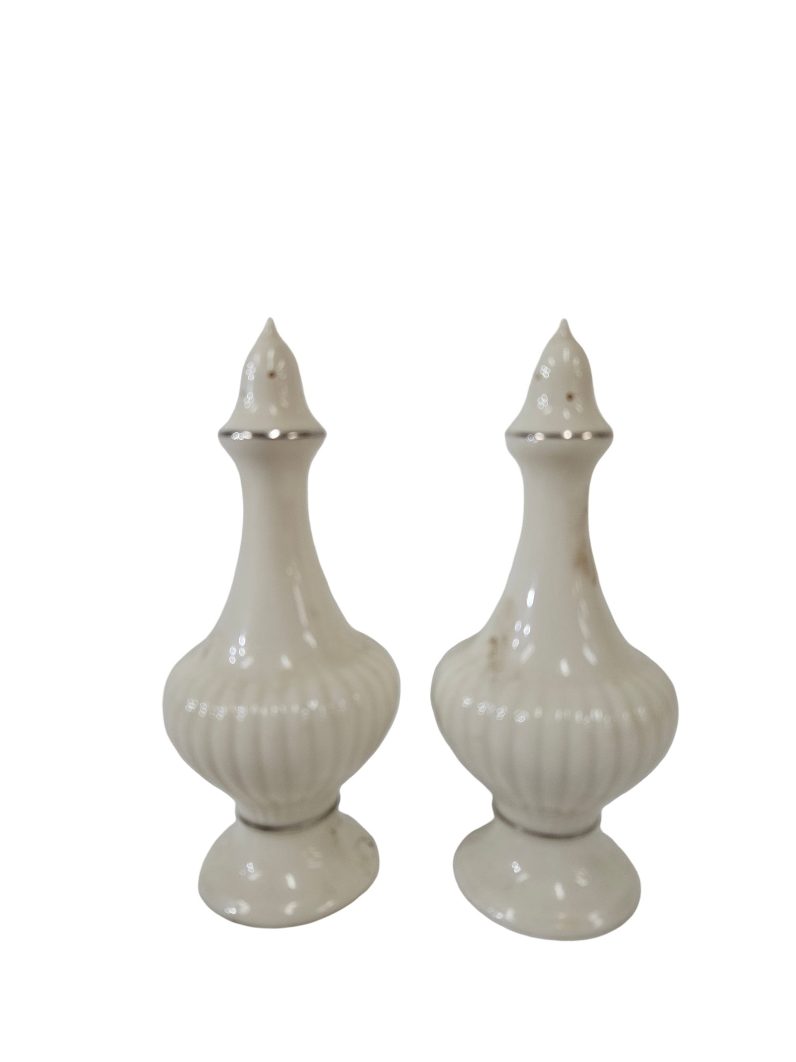 Lenox Porcelain Salt & Pepper Shakers: A pair of tall cream porcelain salt and pepper shakers featuring a ribbed bulbous base and slender necks. These pieces are accented with silver-toned bands at the neck and base for a touch of