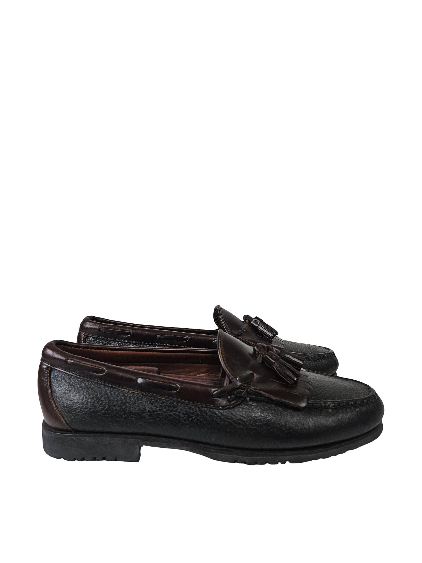Two-Tone Leather Kiltie Tassel Loafers: Pair of two-tone leather kiltie tassel loafers featuring a dark brown upper and pebbled black sides. These slip-on shoes include classic decorative fringe and tassel details with a rubber lug sole