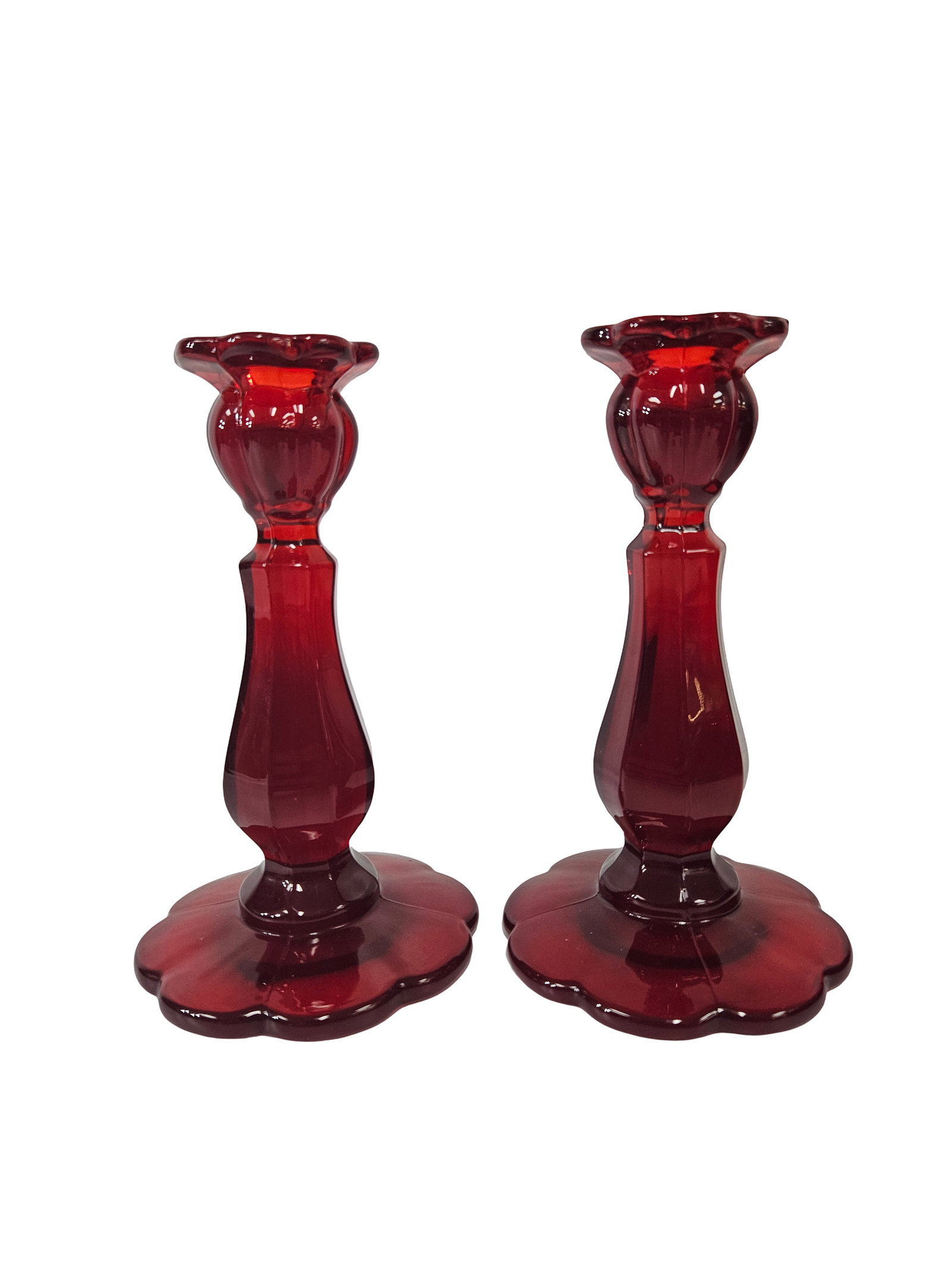 Pair of Ruby Red Paneled Glass Holders: This pair of vibrant ruby red glass candlesticks features an elegant paneled stem and scalloped petal-style bases and rims. The pressed glass design catches the light beautifully, showcasing a deep