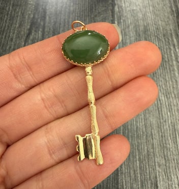 Vintage Jade and 14K Gold Bamboo Style Key Pendant: A striking vintage key pendant featuring a smooth green jade cabochon set in a 14K yellow gold bamboo-textured frame and stem.