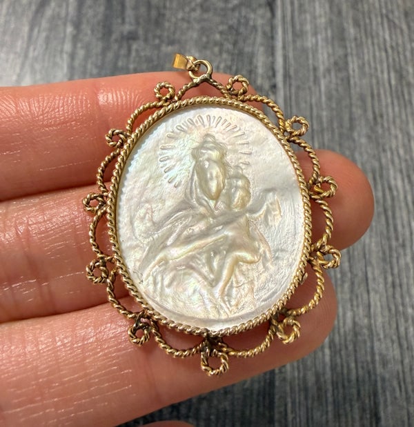 Vintage Carved Mother of Pearl Virgin Mary Pendant: A beautifully carved Mother of Pearl depiction of the Virgin Mary, encased in a decorative 18K yellow gold frame.