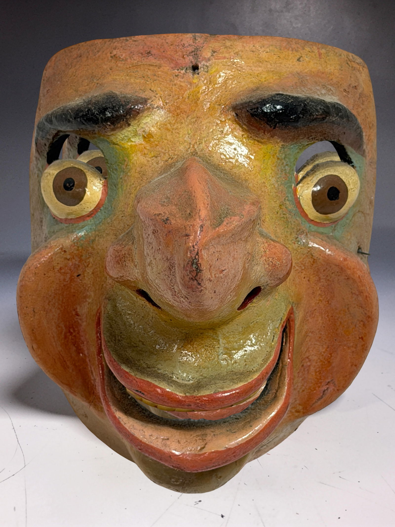 Antique Handcrafted Wood Mask: Antique Handcrafted Wood Mask with exaggerated facial features and painted surface.