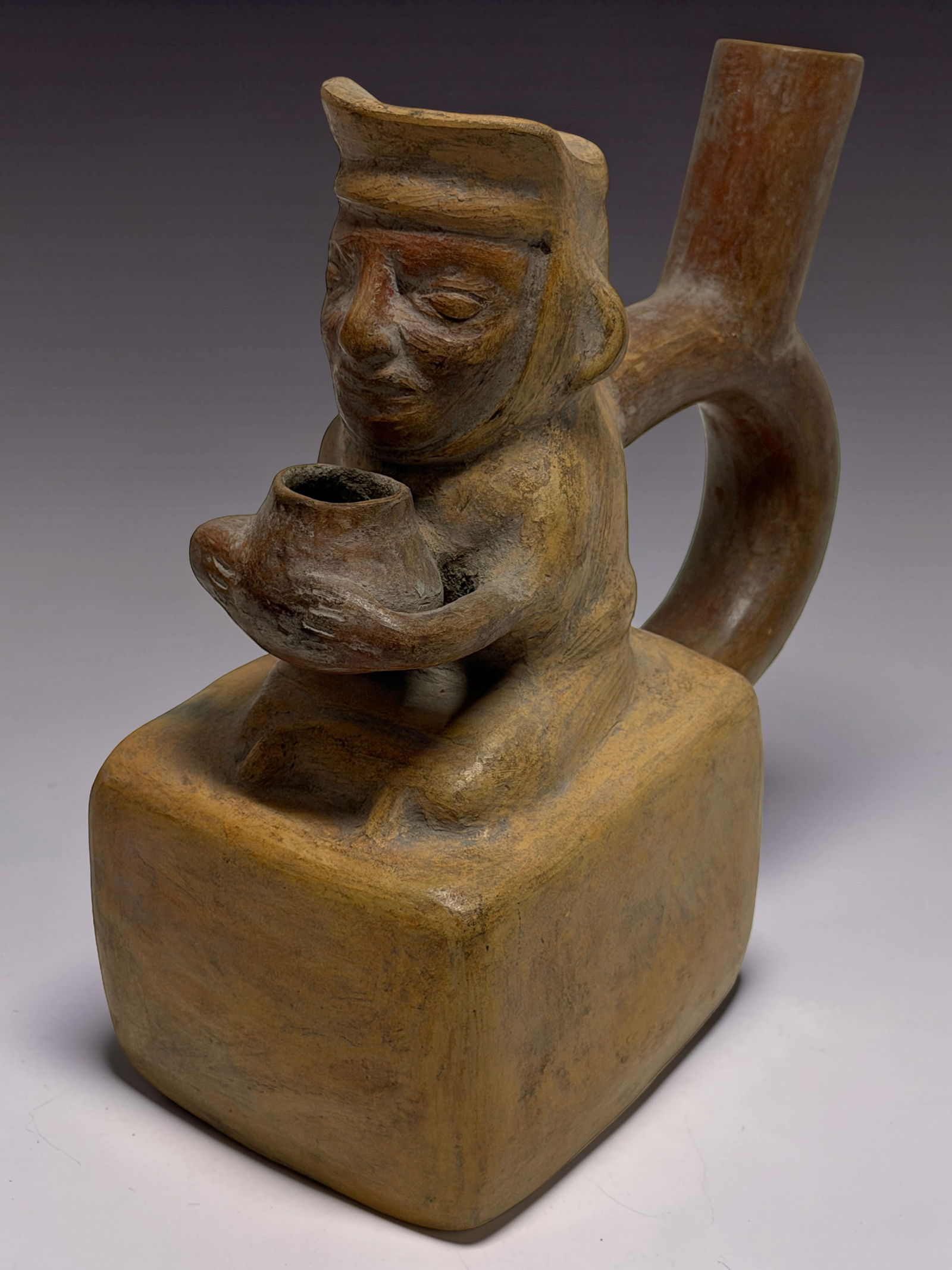 Pre-Columbian Stirrup Vessel: Ceramic stirrup-spout vessel with seated figure holding cup.