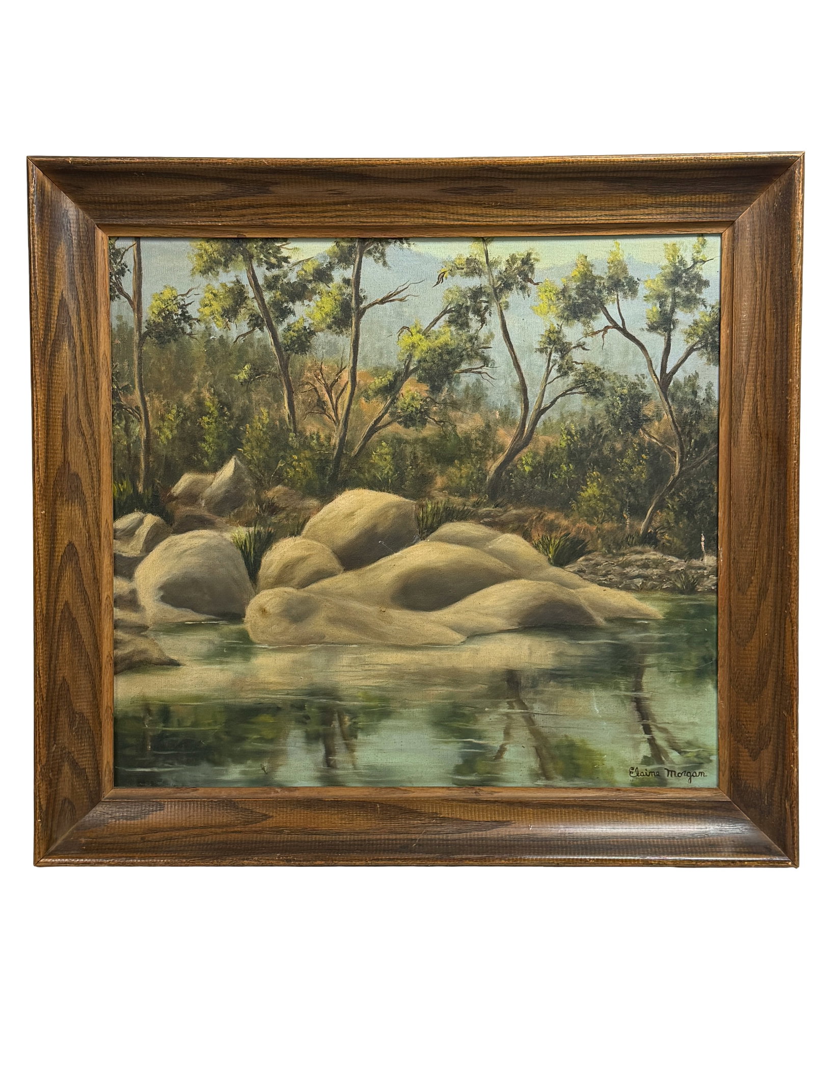 Elaine Morgan, Framed Landscape Oil Painting of River and Boulders: Naturalistic landscape painting showing a quiet river with large rounded boulders and trees along the bank. Signed ?Elaine Morgan? lower right. Oil on canvas, presented in a substantial wood frame.