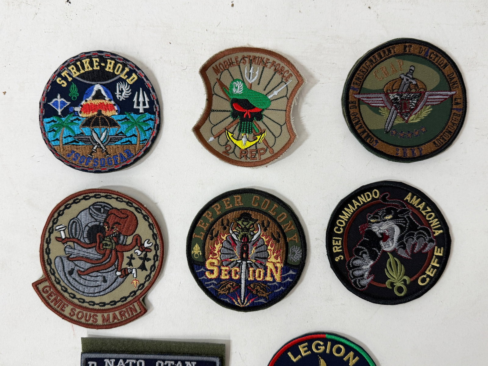 Collection of Military Embroidered Patches: Mixed lot of embroidered military and foreign legion patches, including French Foreign Legion commando units, special forces insignia, training centers, and marine units. Features various designs such