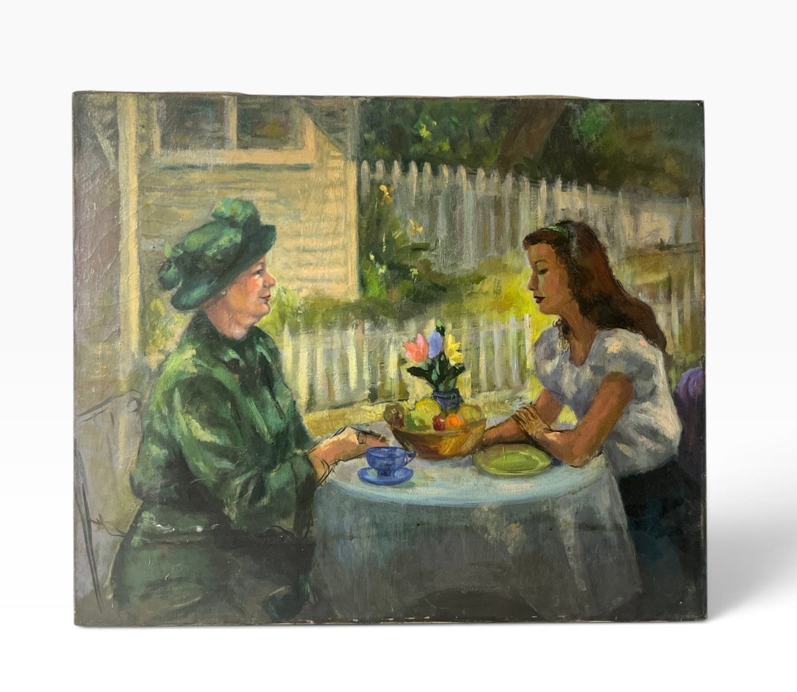 Vintage Figural Painting Two Women at Garden Table: Vintage genre painting depicting two women seated at an outdoor table with teacup, fruit and flowers, set before a white picket fence and house. Artist signature not visible in provided image. Unframe