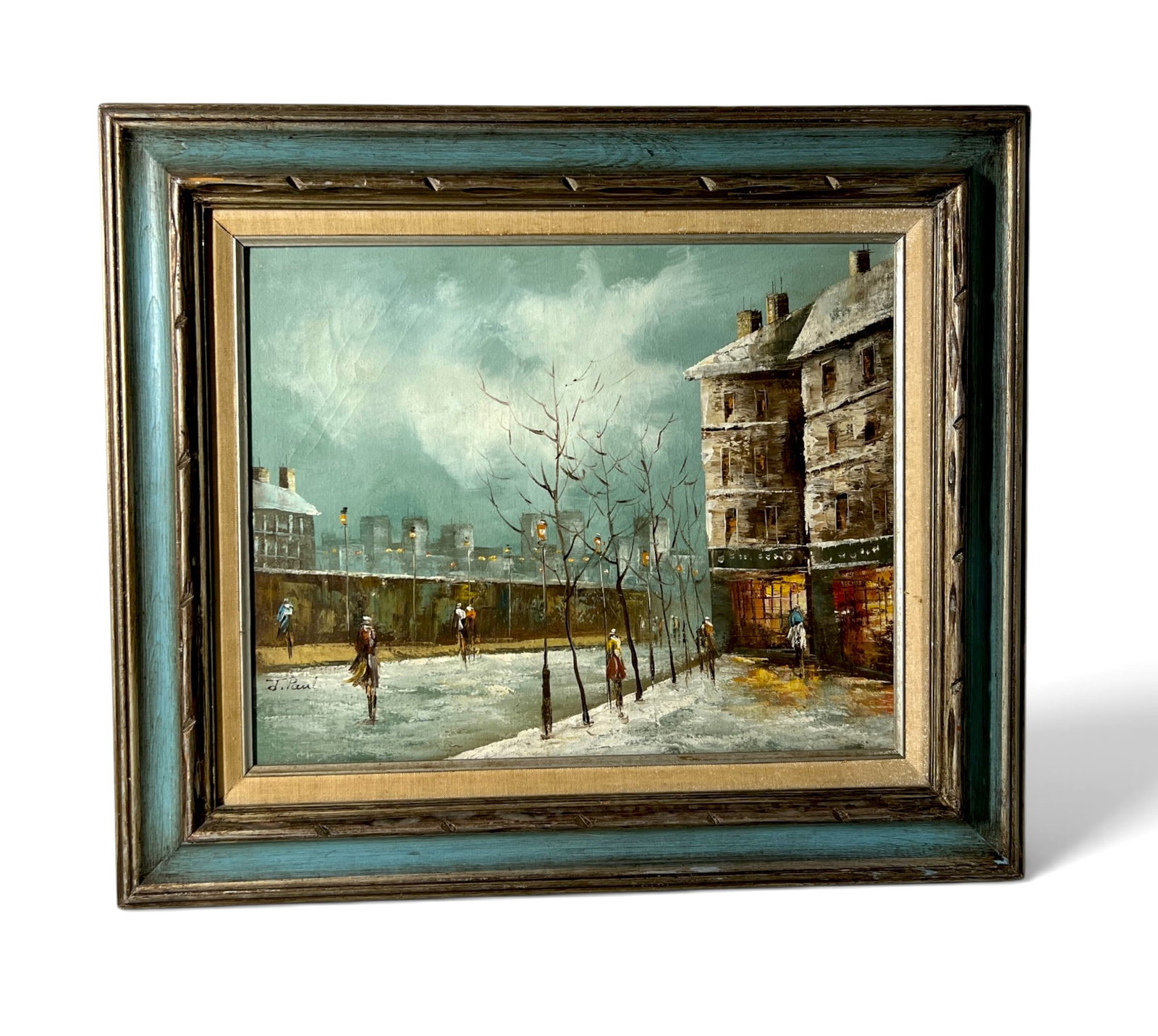 J Paul Signed Winter Paris Street Scene Oil Painting: Framed winter cityscape depicting a snow-covered European street or square with figures, bare trees, glowing shopfronts and distant architecture under a pale blue-gray sky. Signed 'J. Paul' at lower l