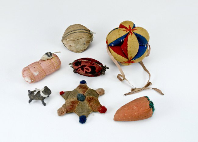 Early Fabric Sewing Pincushions: 6 pincushions measuring from 10 1/2" to 4 1/2", including an early Amish star, also a spun cotton dog. All have use wear.