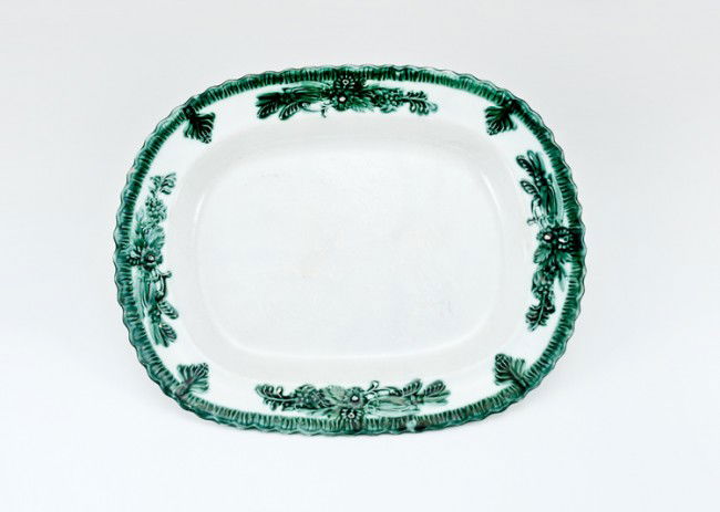 Early Feather Edge Platter: 15" x 11 7/8" green feather edge platter with raised floral decoration, circa late 1800's, small chipping to high spots and use wear to glaze. Maker unknown.